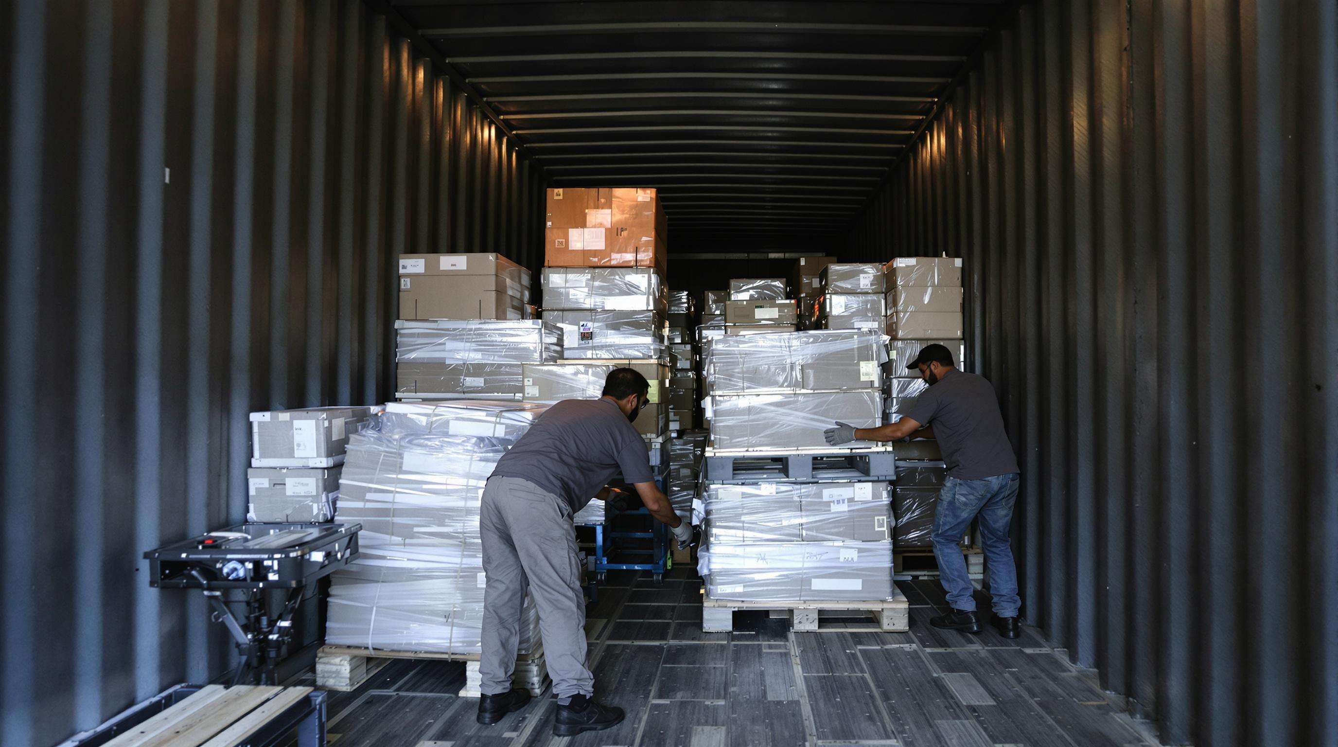 Warehouse workers optimizing cargo packaging with modular crates and nested items for efficient air freight.