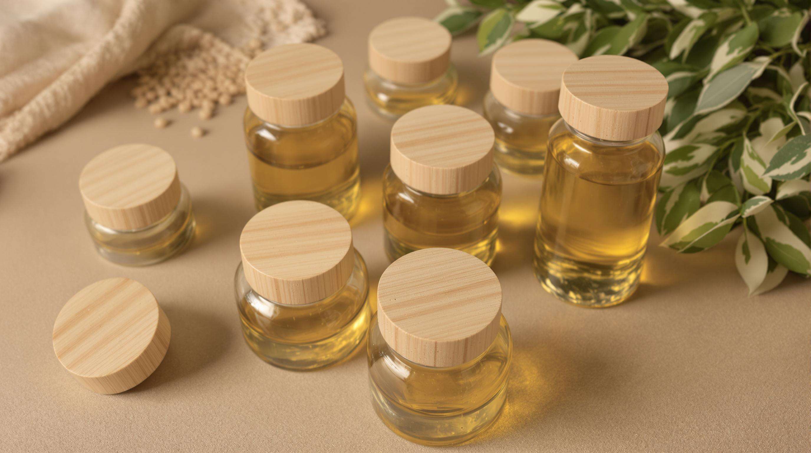 Bulk glass oil bottles with bamboo child-resistant caps displayed on a neutral background with focus on the natural materials