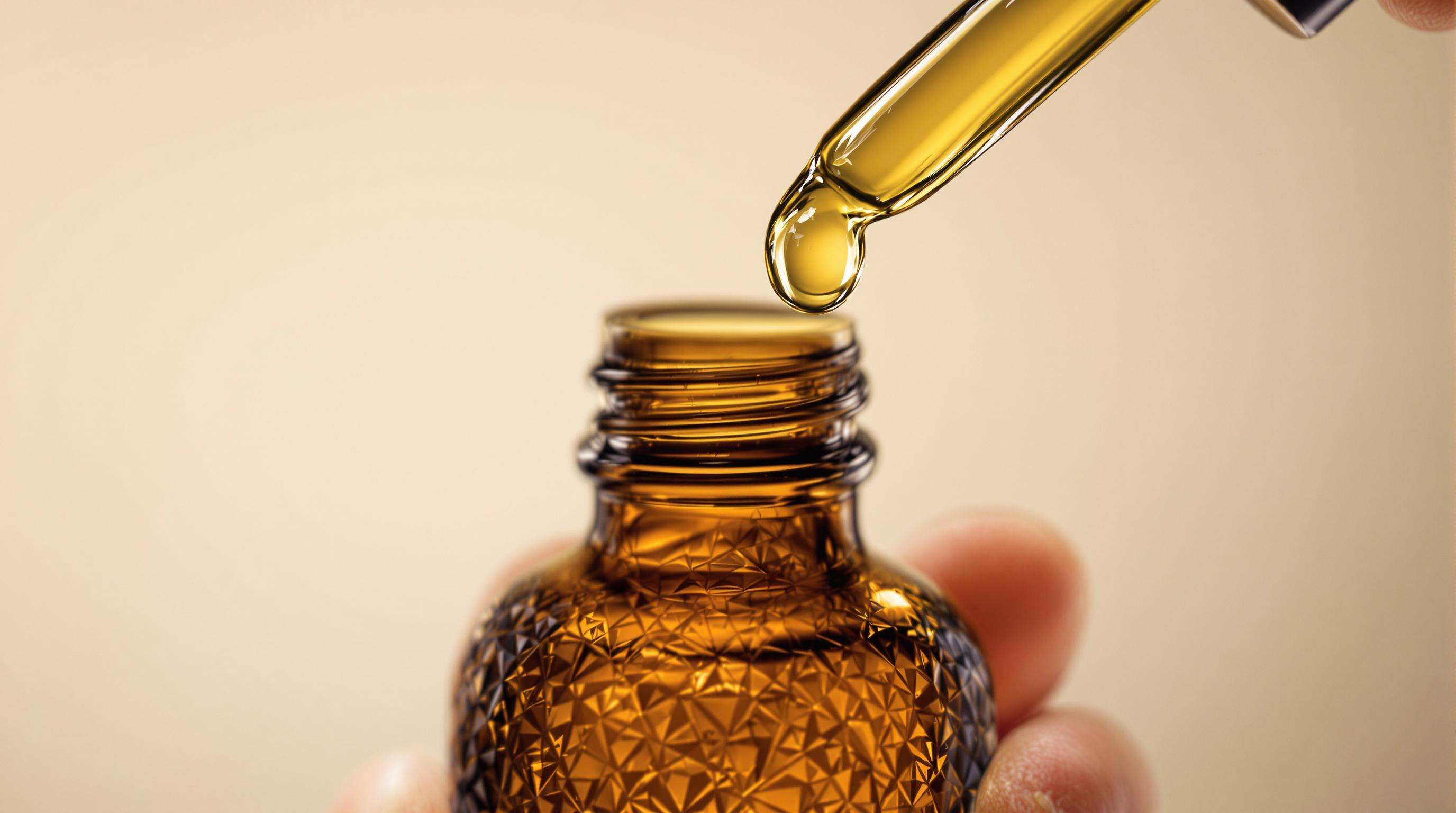 Close-up of an amber glass dropper bottle dispensing oil, highlighting its precise and user-friendly design