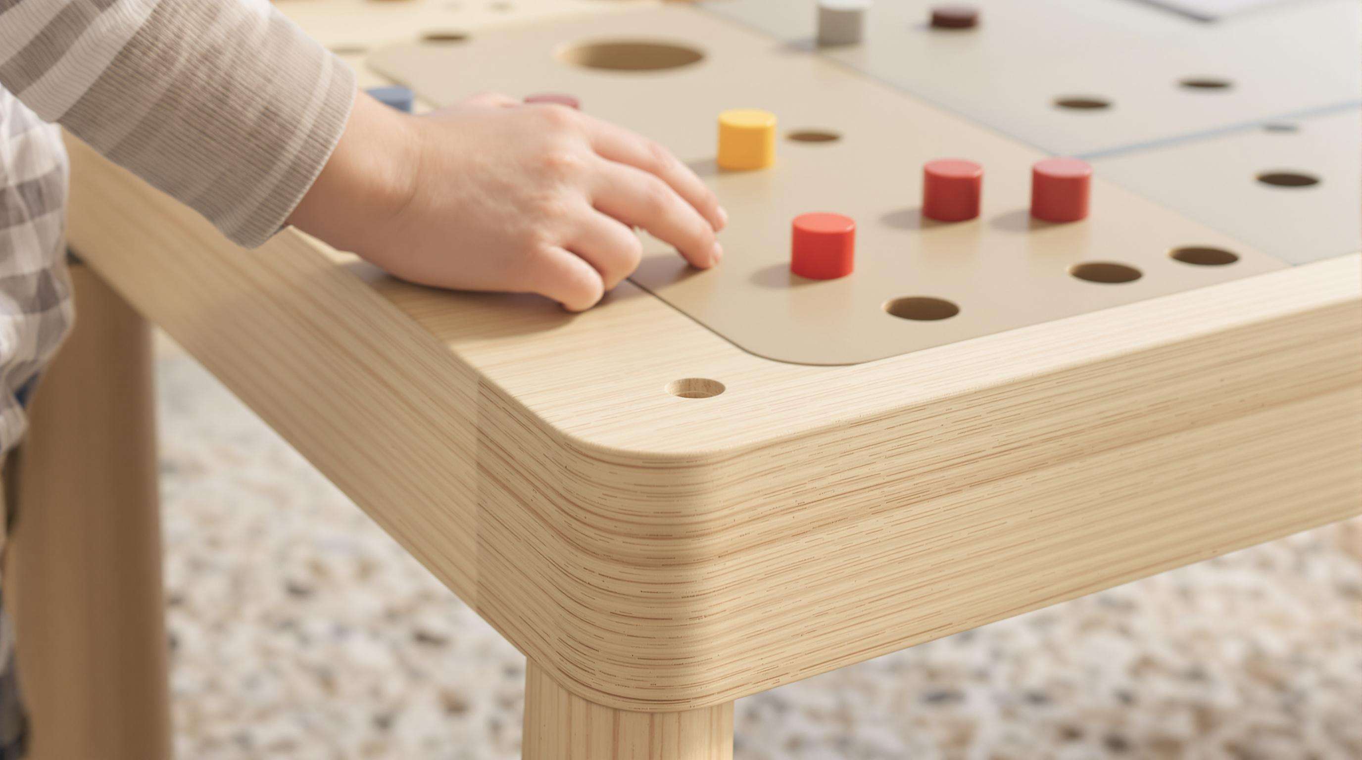 Child’s hand testing a sturdy, safe game table with modular surfaces and rounded edges