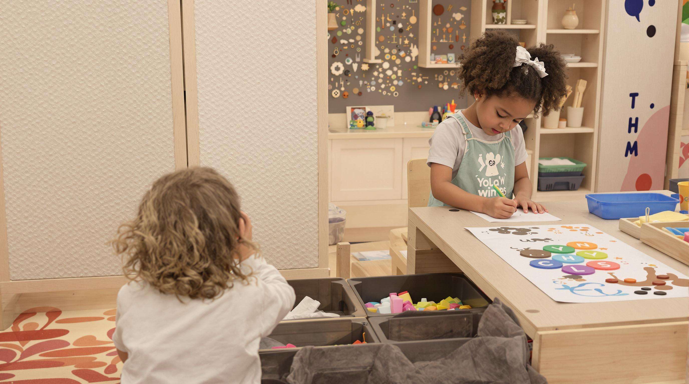 Children using a sensory game table with textured elements and art surfaces for creative play