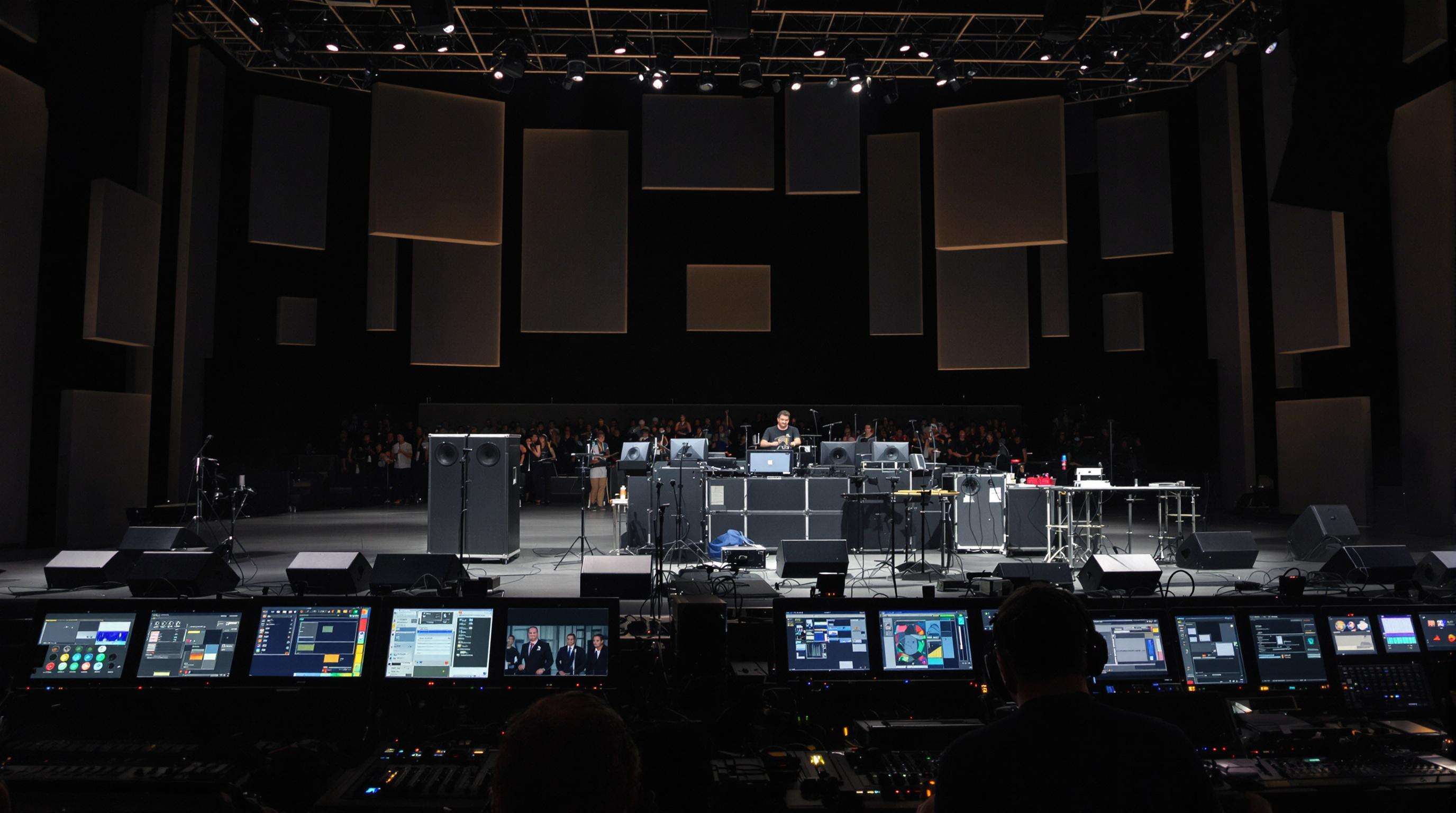 Side-stage view of live concert monitor setup with technician adjusting speakers
