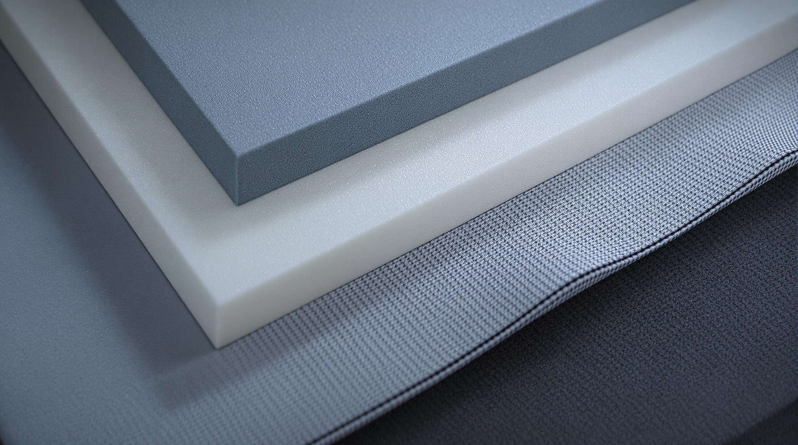 Close-up photo of different back protector materials including polymer foams, composite fibers, and moisture-wicking fabrics on a grey lab table