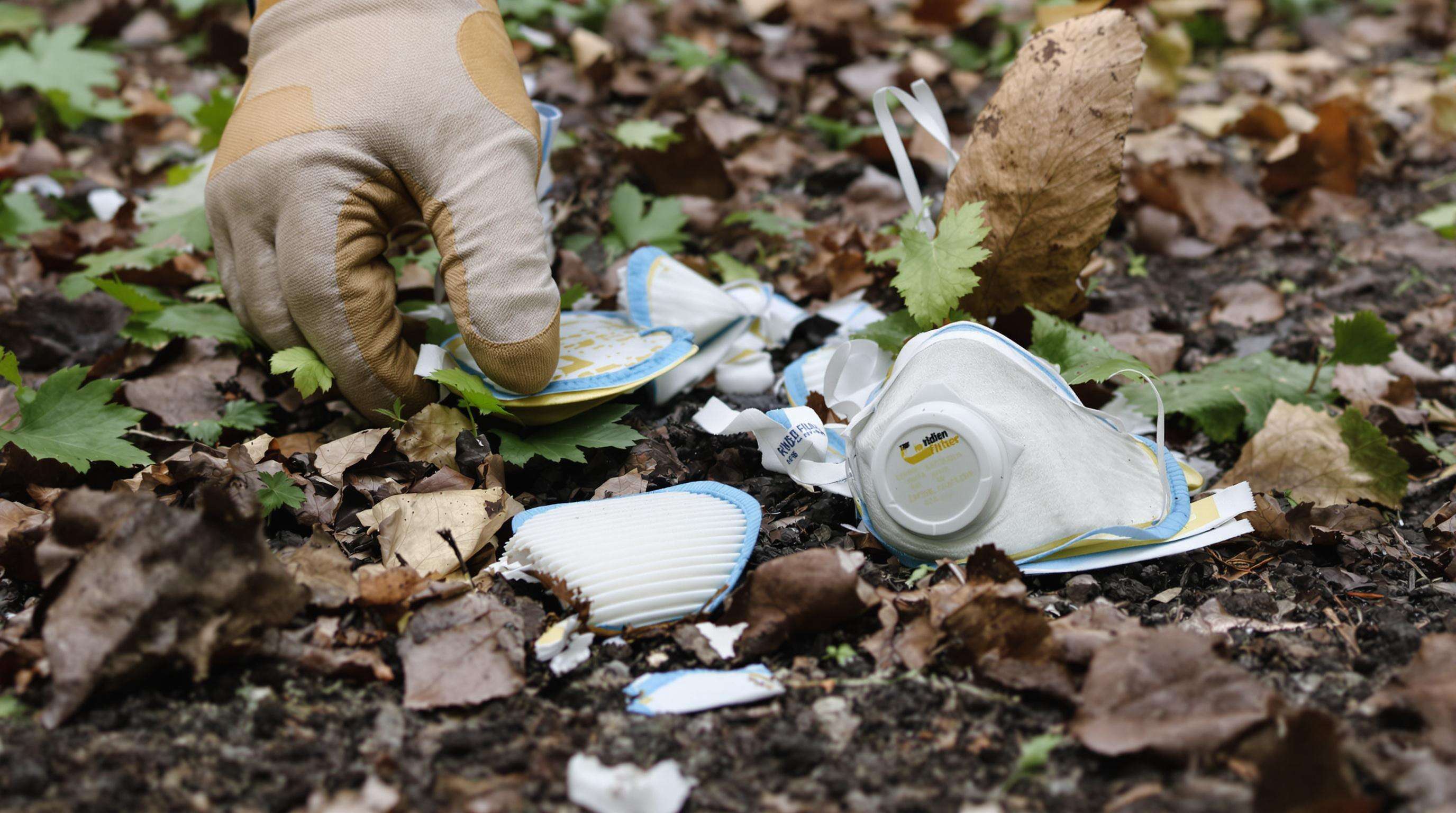 Close-up view of discarded riding mask filters on a forest trail being cleaned by a maintenance worker