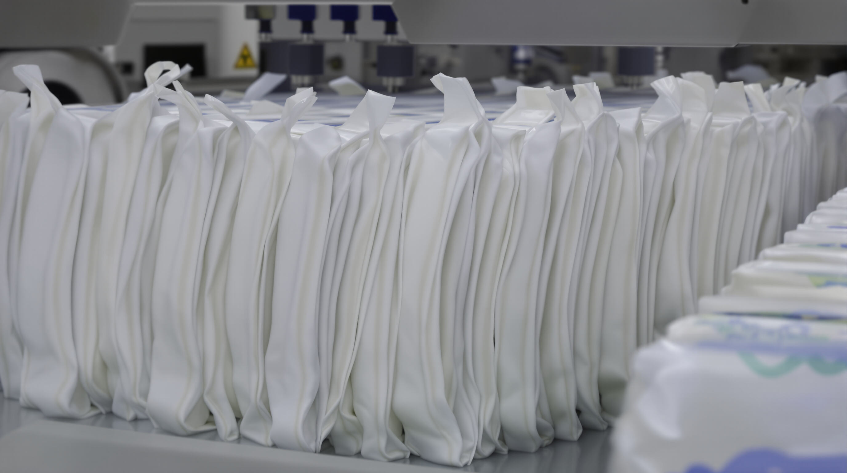 Modern production line vacuum-sealing compact diaper packs, highlighting space-saving design