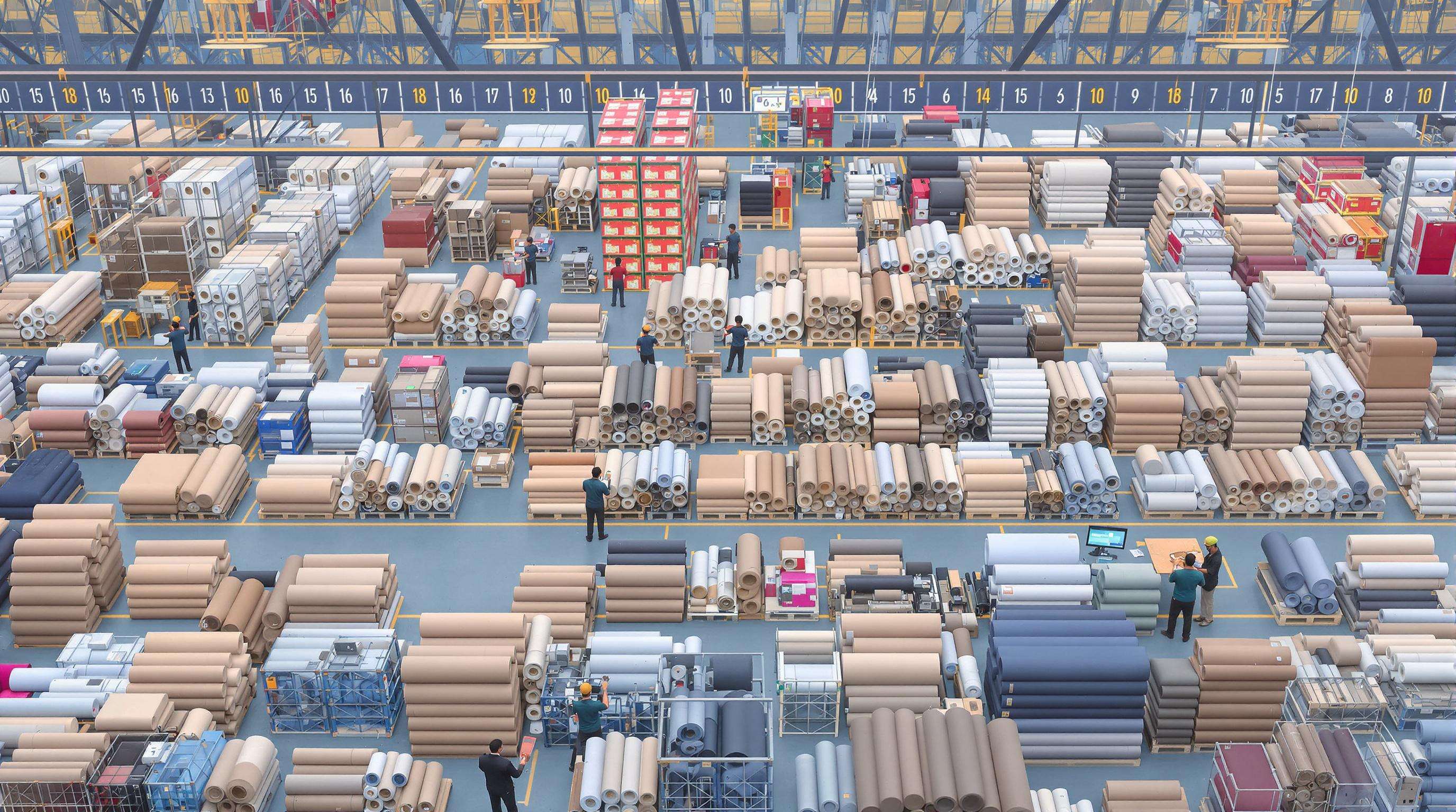Warehouse scene with stacked synthetic leather rolls and workers checking quality