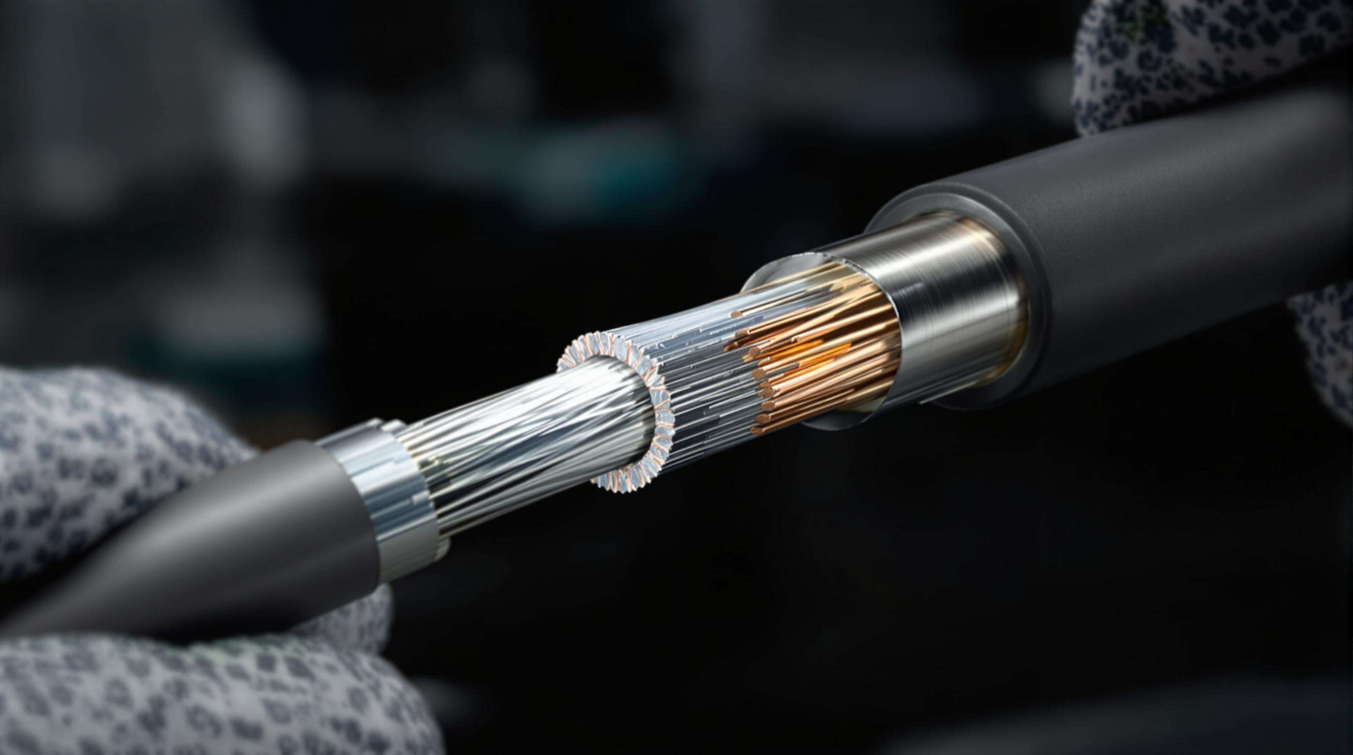 A close-up of a CCAM coaxial cable cross-section displaying aluminum core and copper cladding with technician handling it
