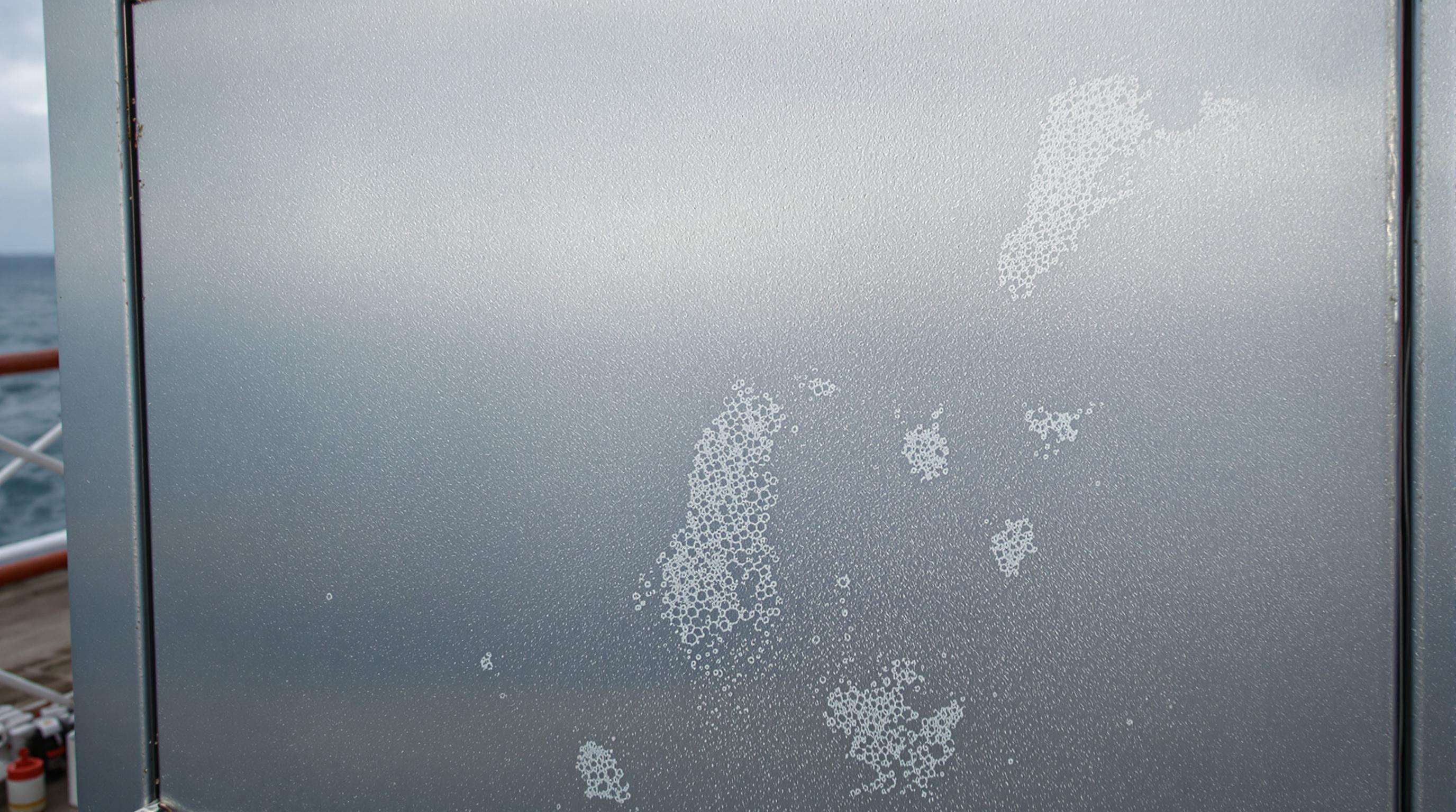 Steel cabinet in a humid coastal setting showing salt deposits and biofilm on metal surface