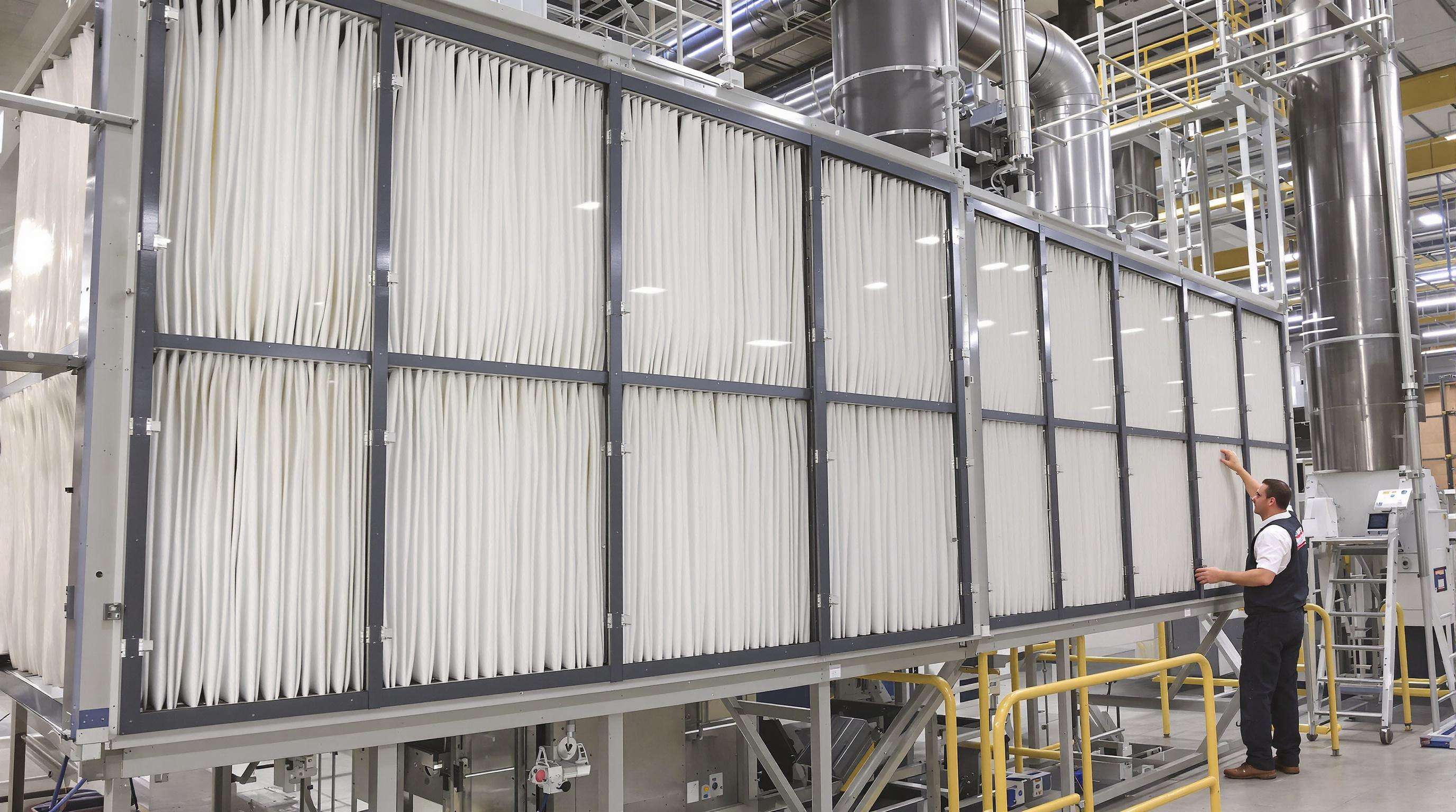 Technicians installing pleated bag filters into a large industrial dust collection unit