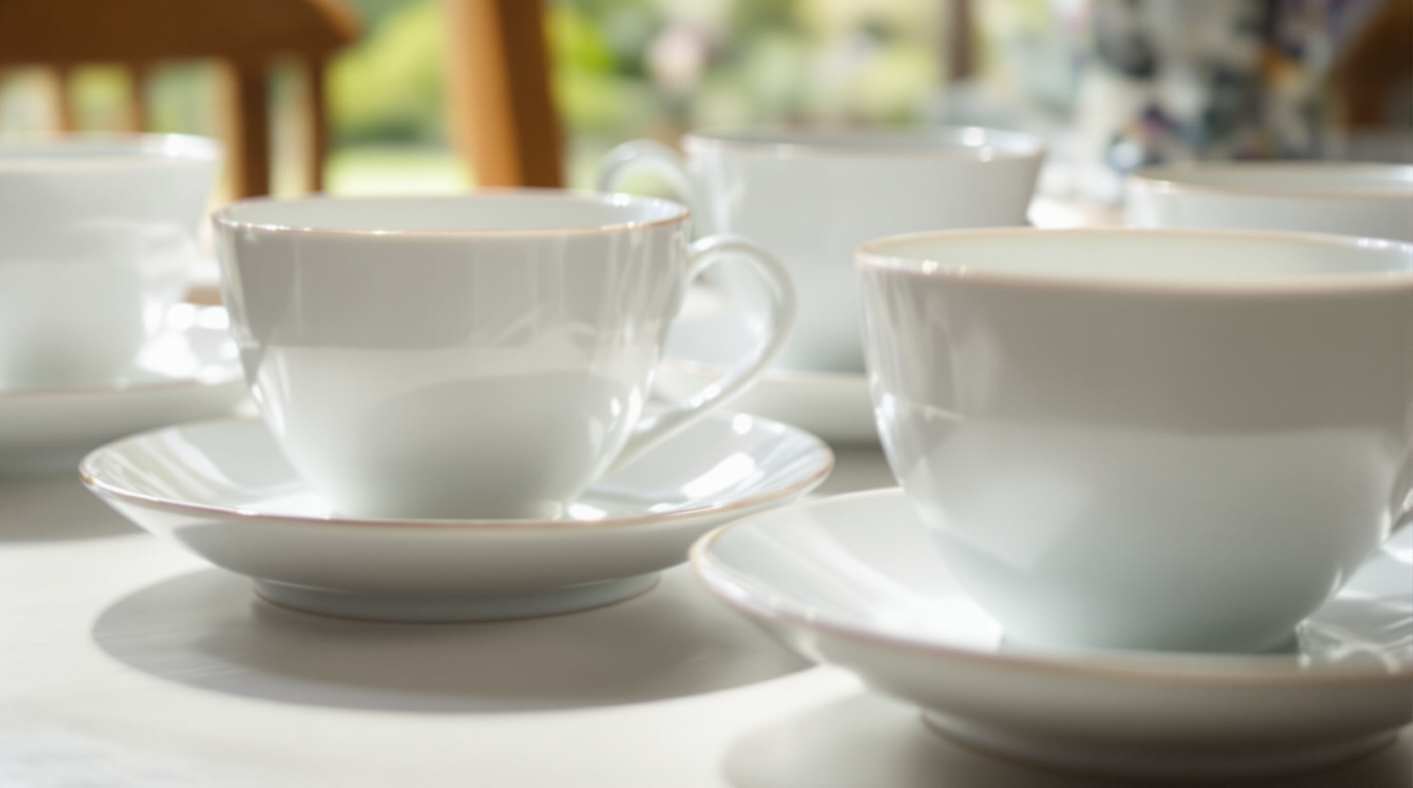 Thin porcelain teacups on a table with light shining through, highlighting their translucency and smooth finish