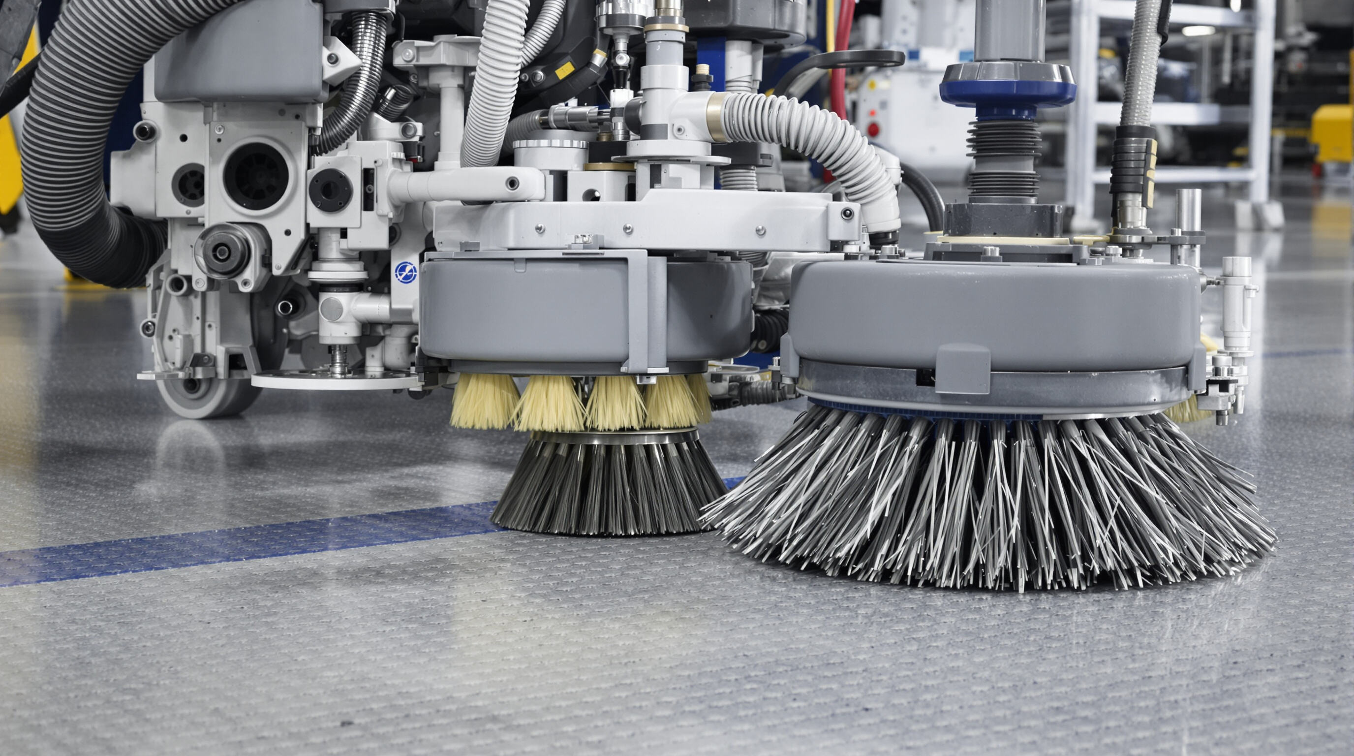 Technician adjusting modular brushes on a floor cleaning machine in a factory