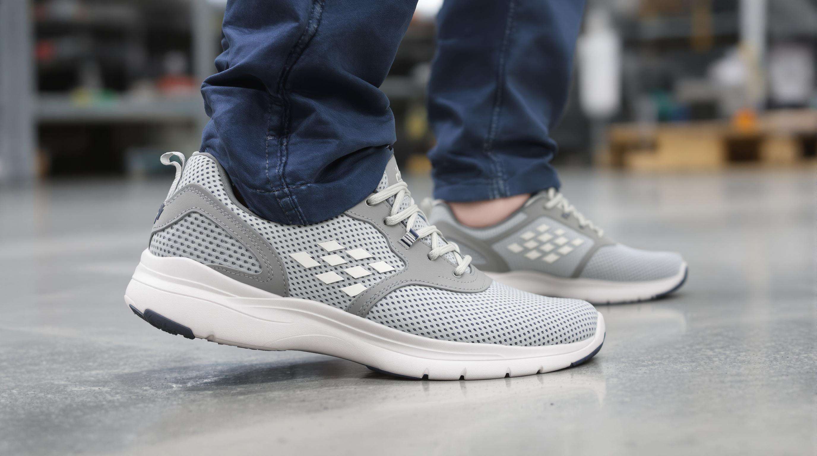 A worker walking in comfortable, cushioned safety sneakers on a factory floor, highlighting ergonomic and breathable design.