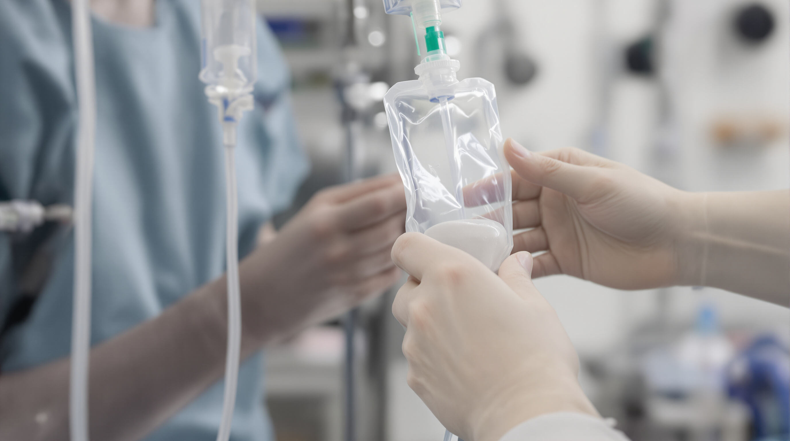Close-up of a medical professional inflating a pressure infusion bag around an IV fluid container in a hospital setting