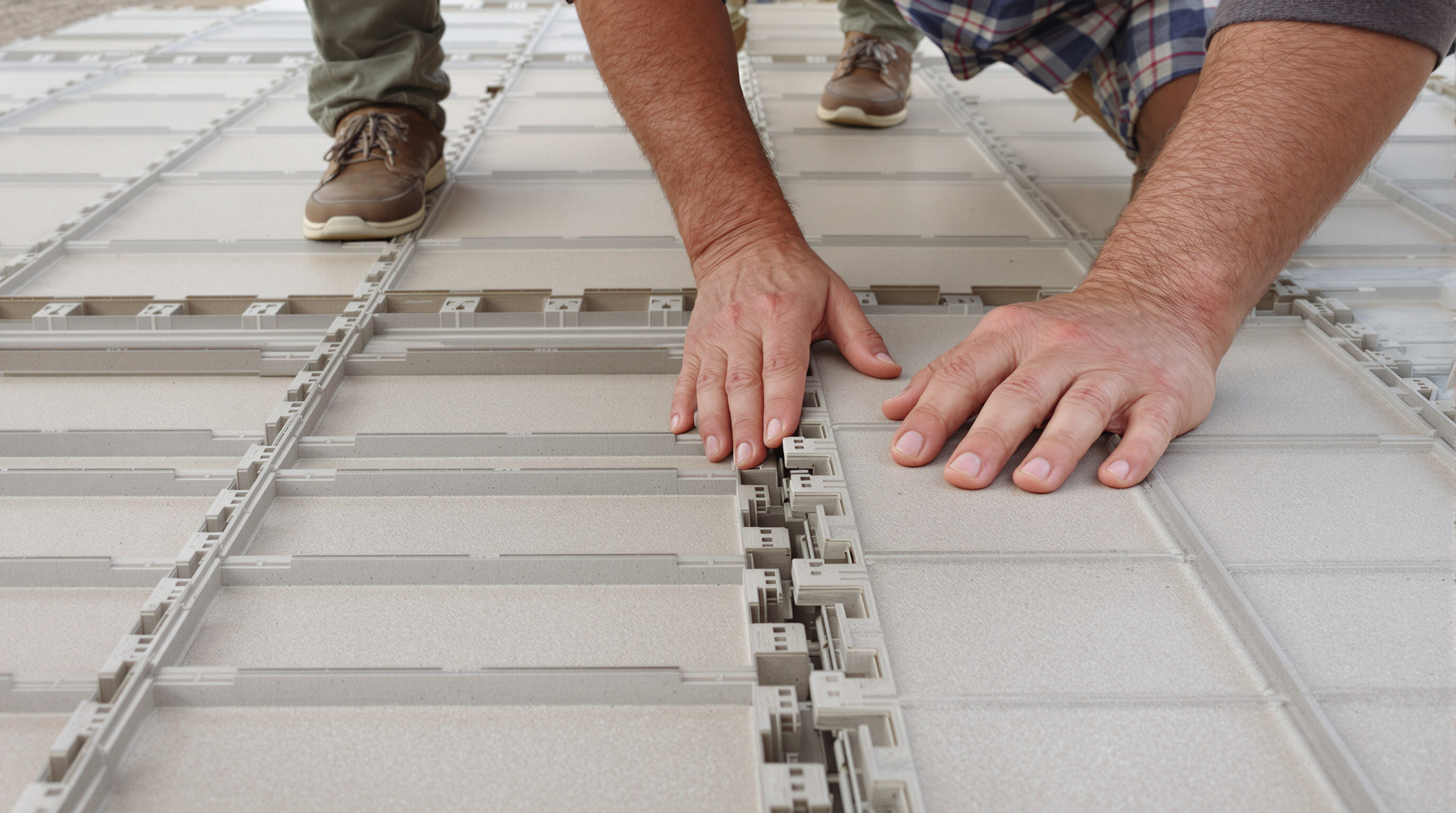 People assembling lightweight, interlocking modular flooring tiles outdoors