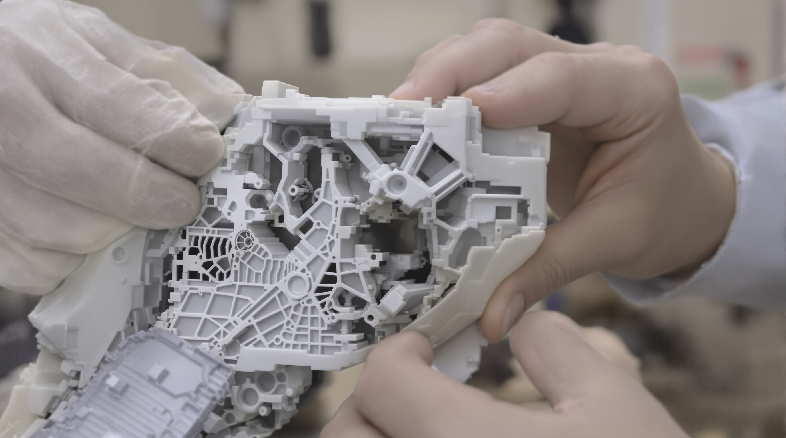 Technician flexing a detailed silicone mold off a complex mechanical part in a workshop