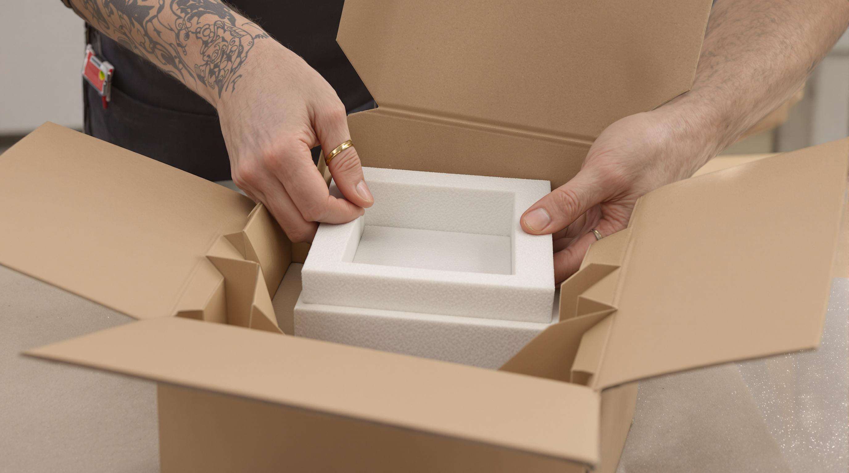 Hands assembling a durable gift box with corrugated inserts, reinforced corners, and foam support