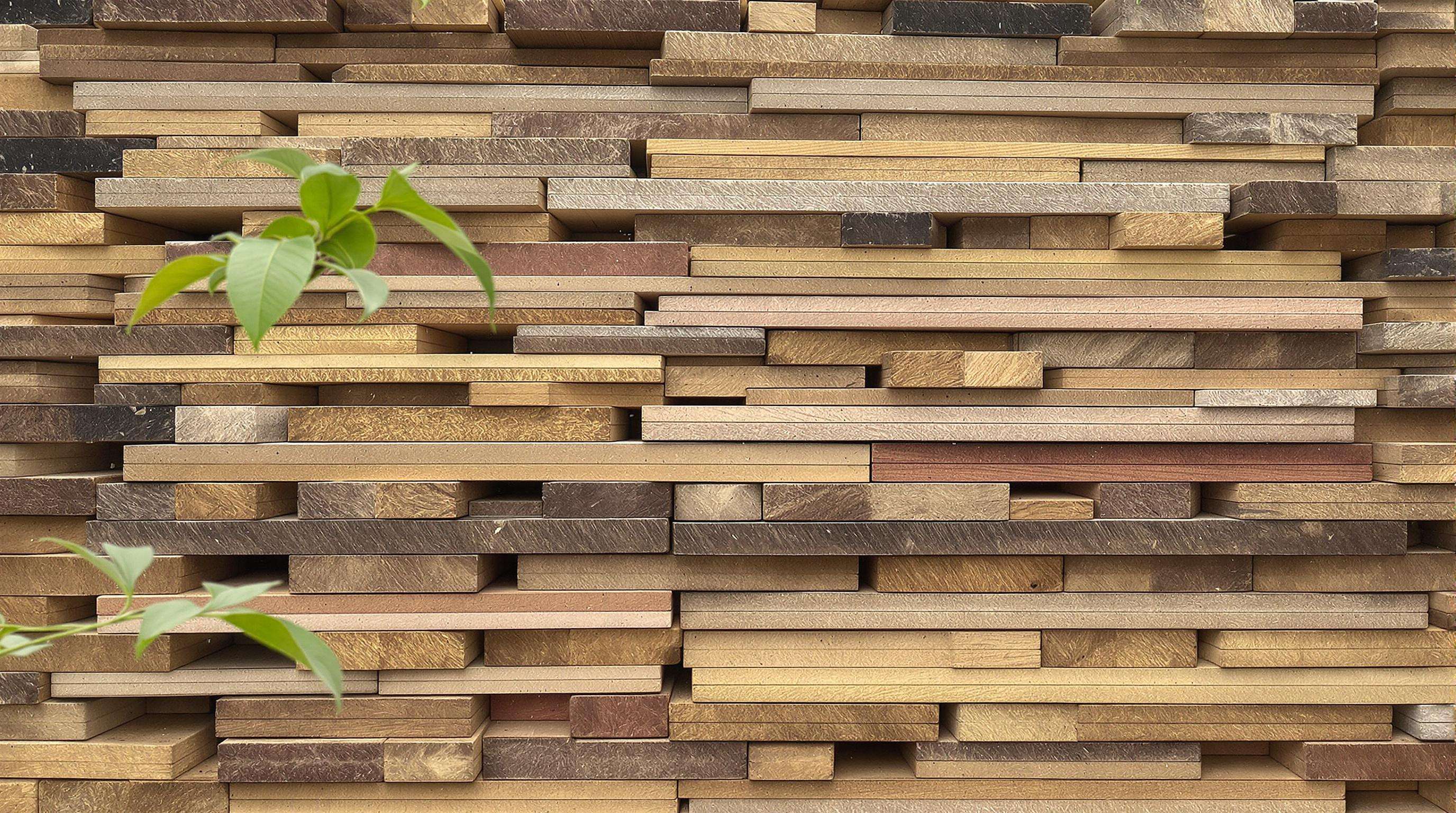 Stacked lumber boards of different thicknesses, with some spaces between, in a humid outdoor setting