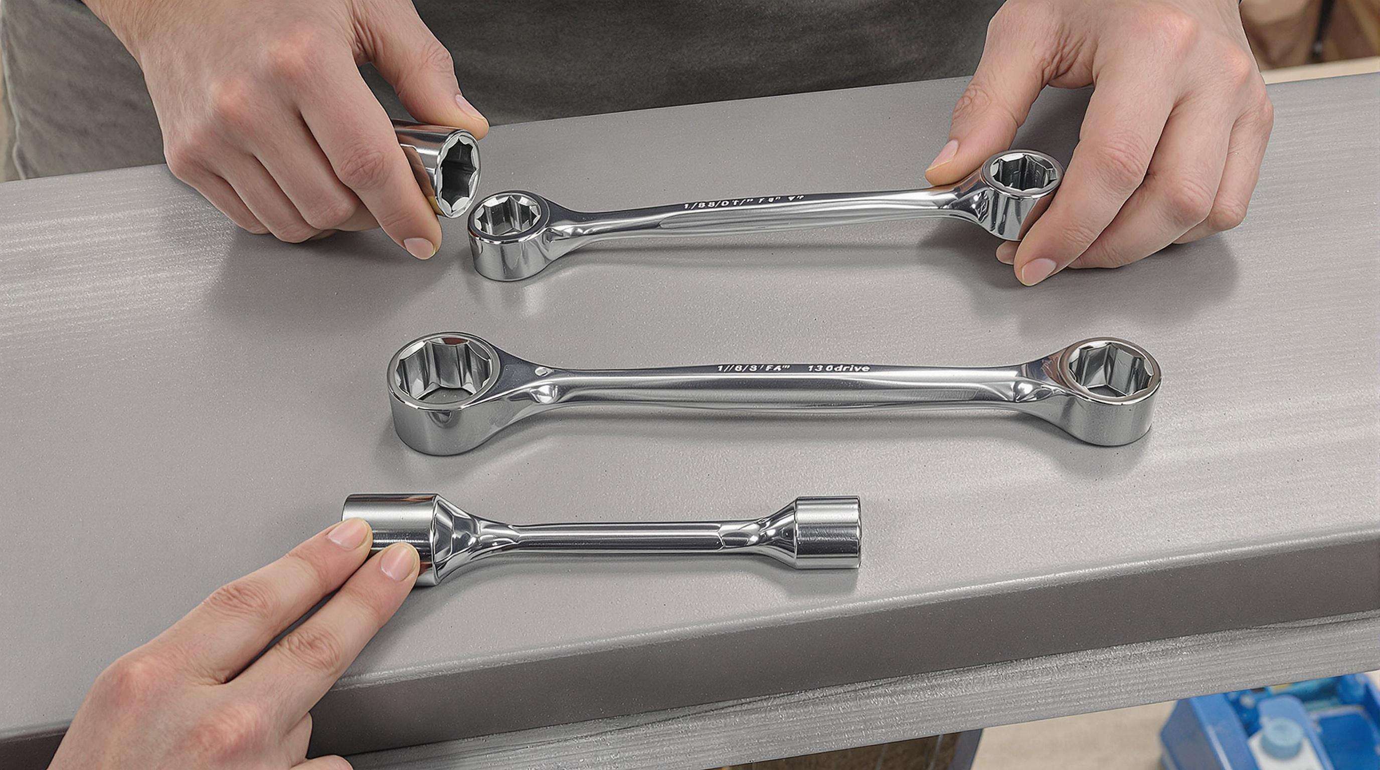 Assortment of socket wrenches in different drive sizes on a workbench with hands demonstrating socket changes
