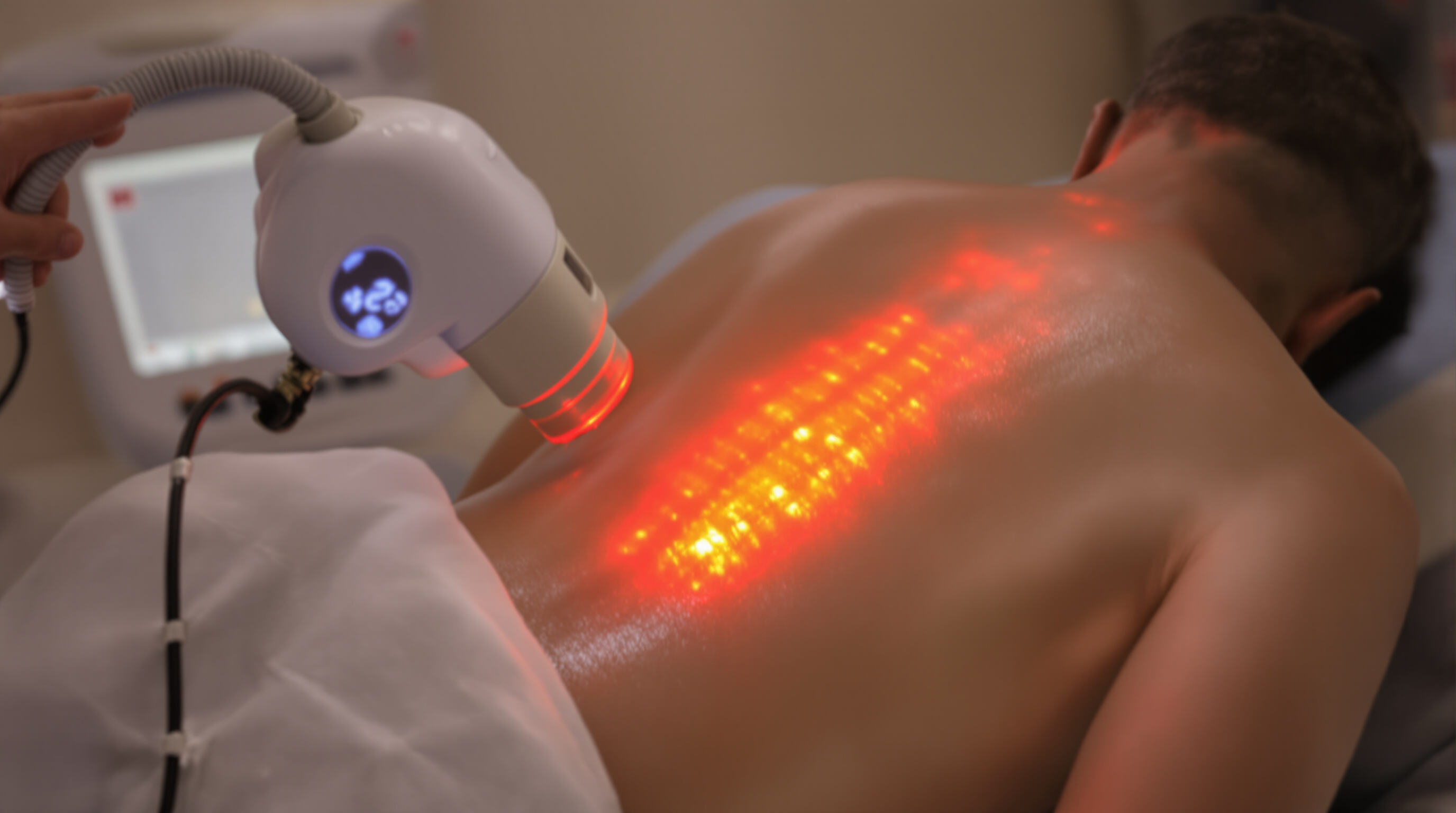 Patient receiving combined red and infrared light therapy on the lower back in a clinical environment