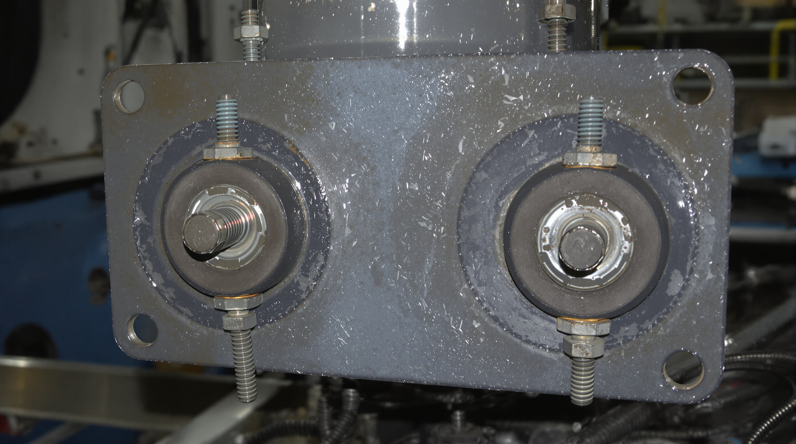 Bolted metal assembly using rubber washers to distribute load and prevent wear in industrial machinery