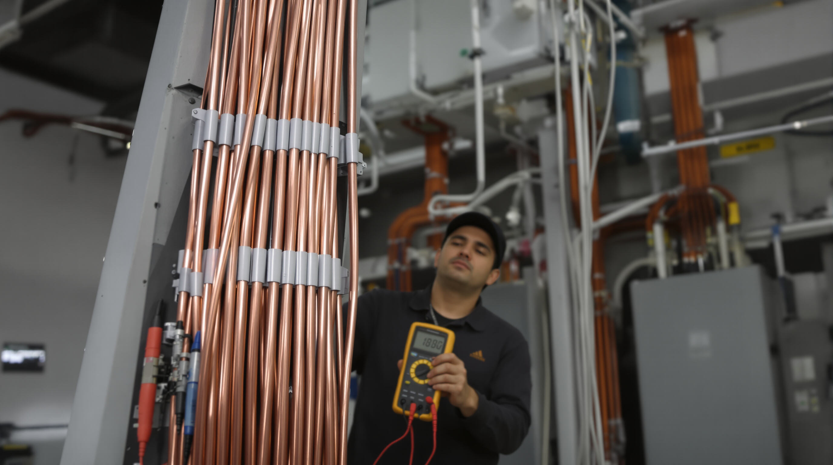 Photorealistic image of a technician inspecting thick copper cables in a high-rise electrical riser