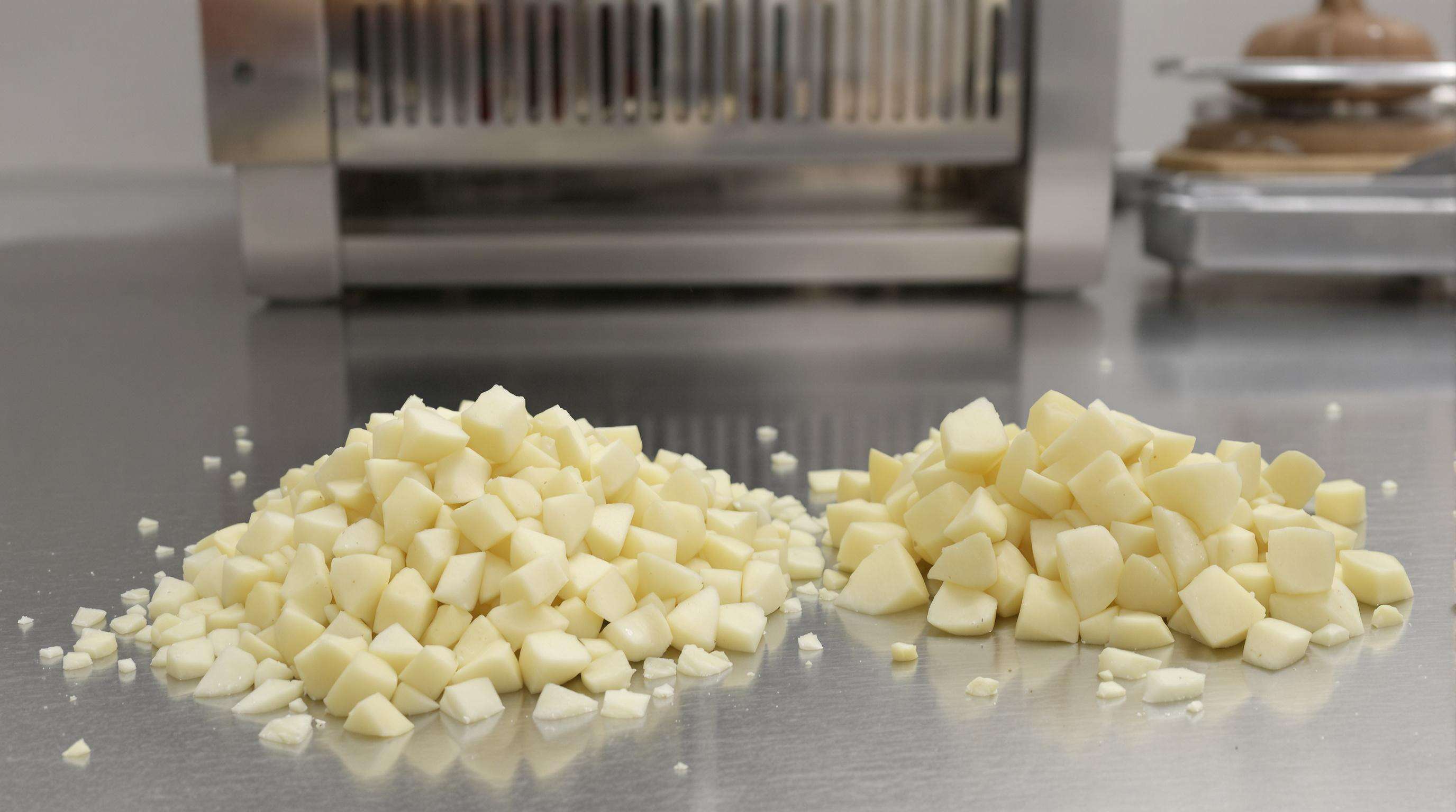 Uniformly diced potatoes and a small pile of scraps on a prep counter beside an automated dicing machine, illustrating reduced waste through automation