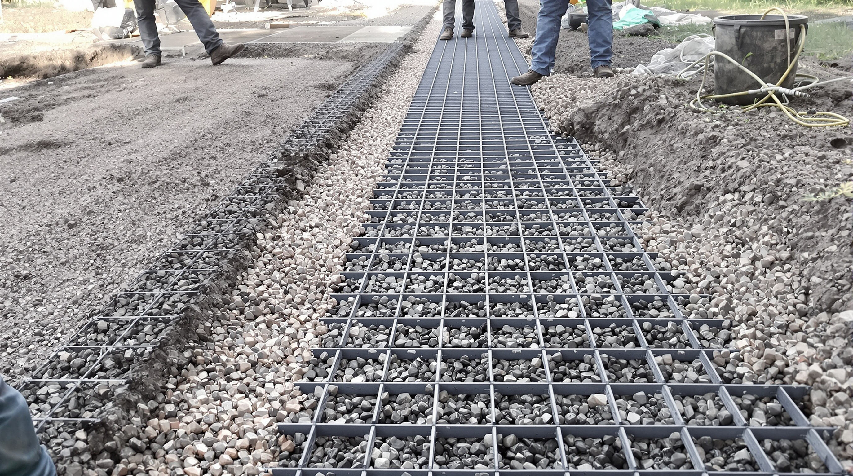 Step-by-step scene displaying workers preparing ground, placing plastic grids, and filling with gravel for installation