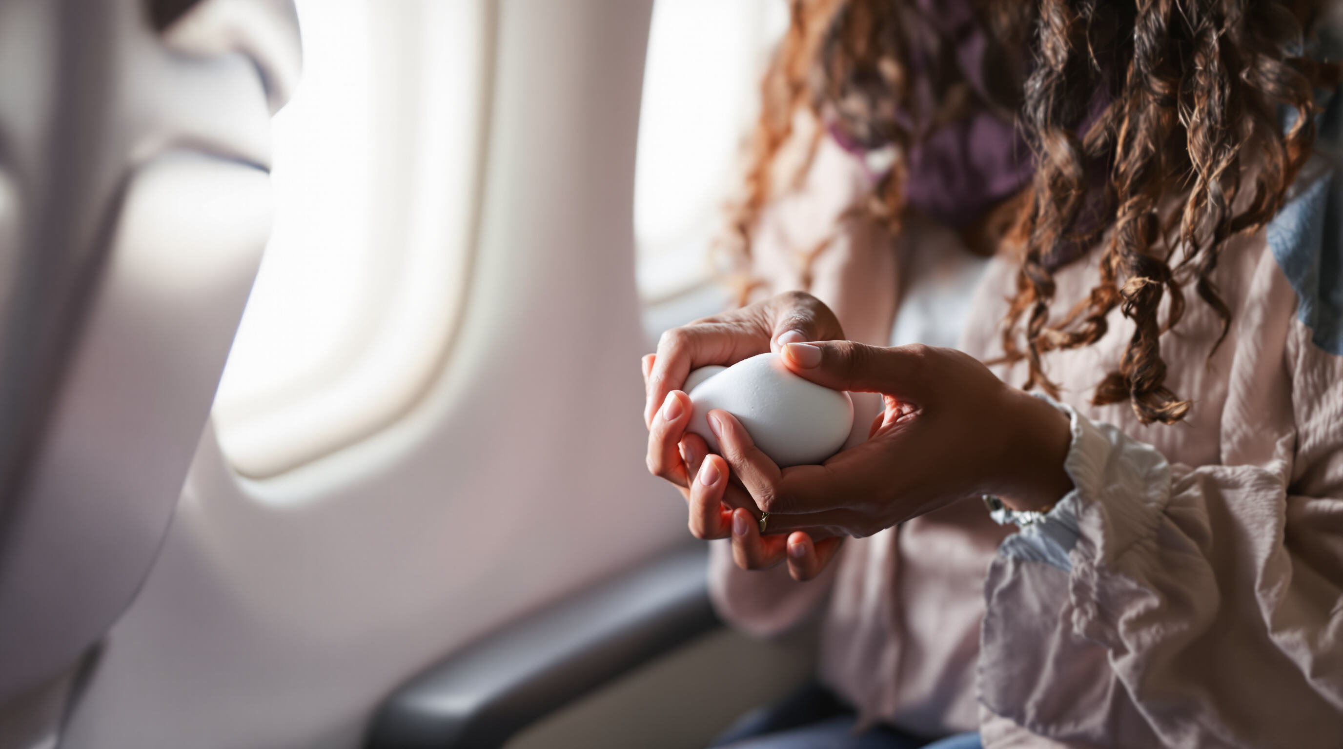 Traveler squeezing a foam squishy for stress relief on a flight
