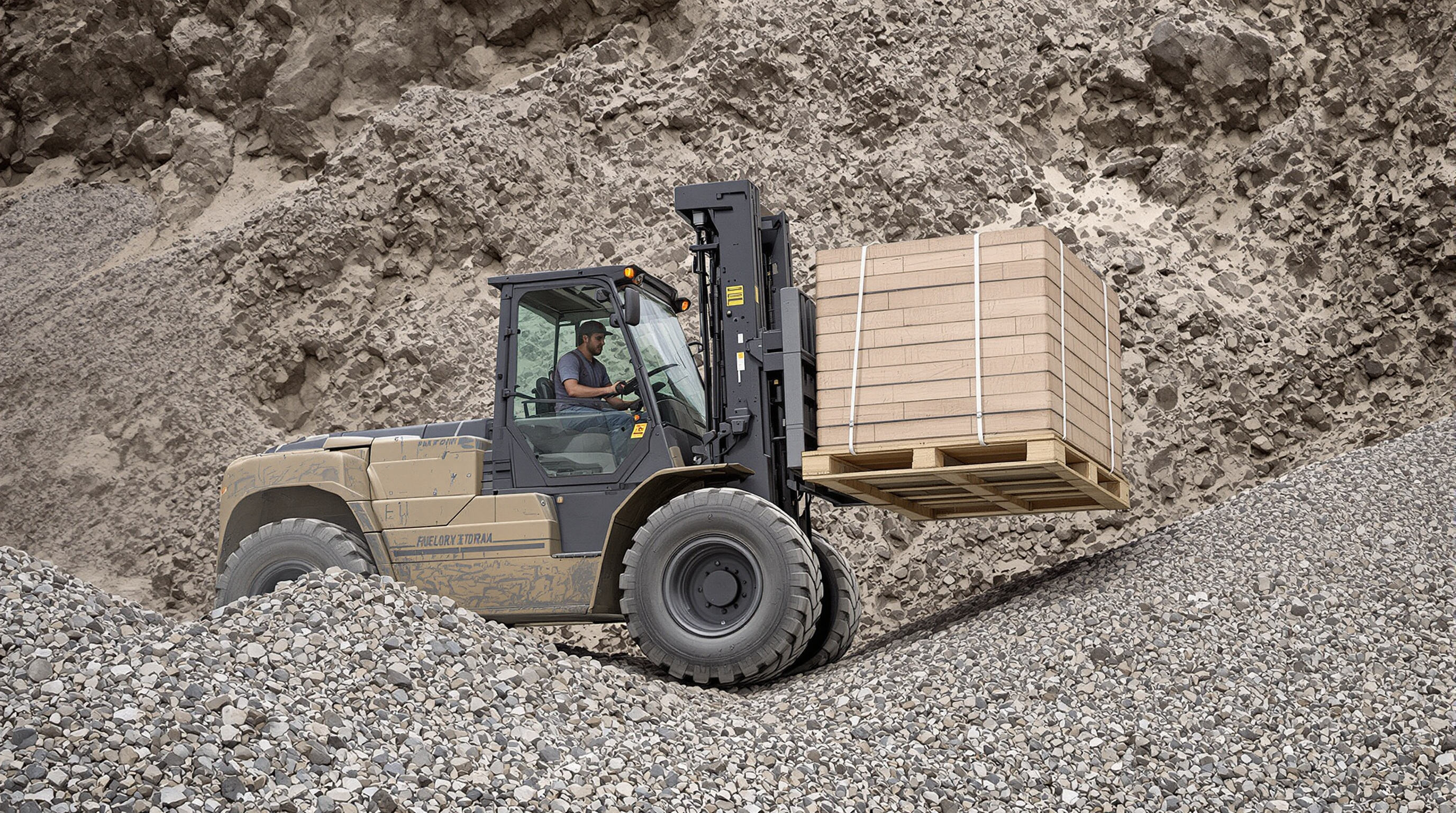 An all-terrain forklift driving across rocky, sloped ground with a large load and wide tires