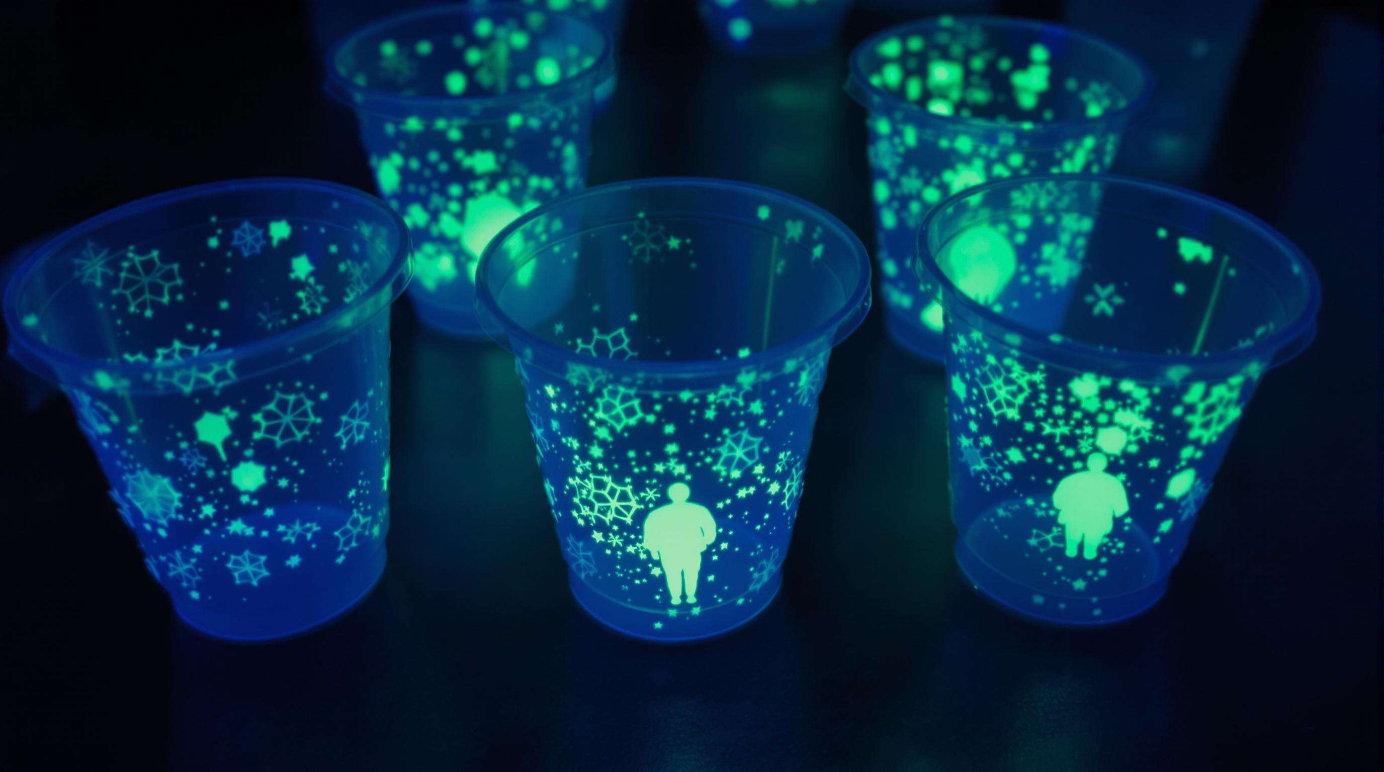 Close-up of glowing party cups showing photoluminescent material under UV light