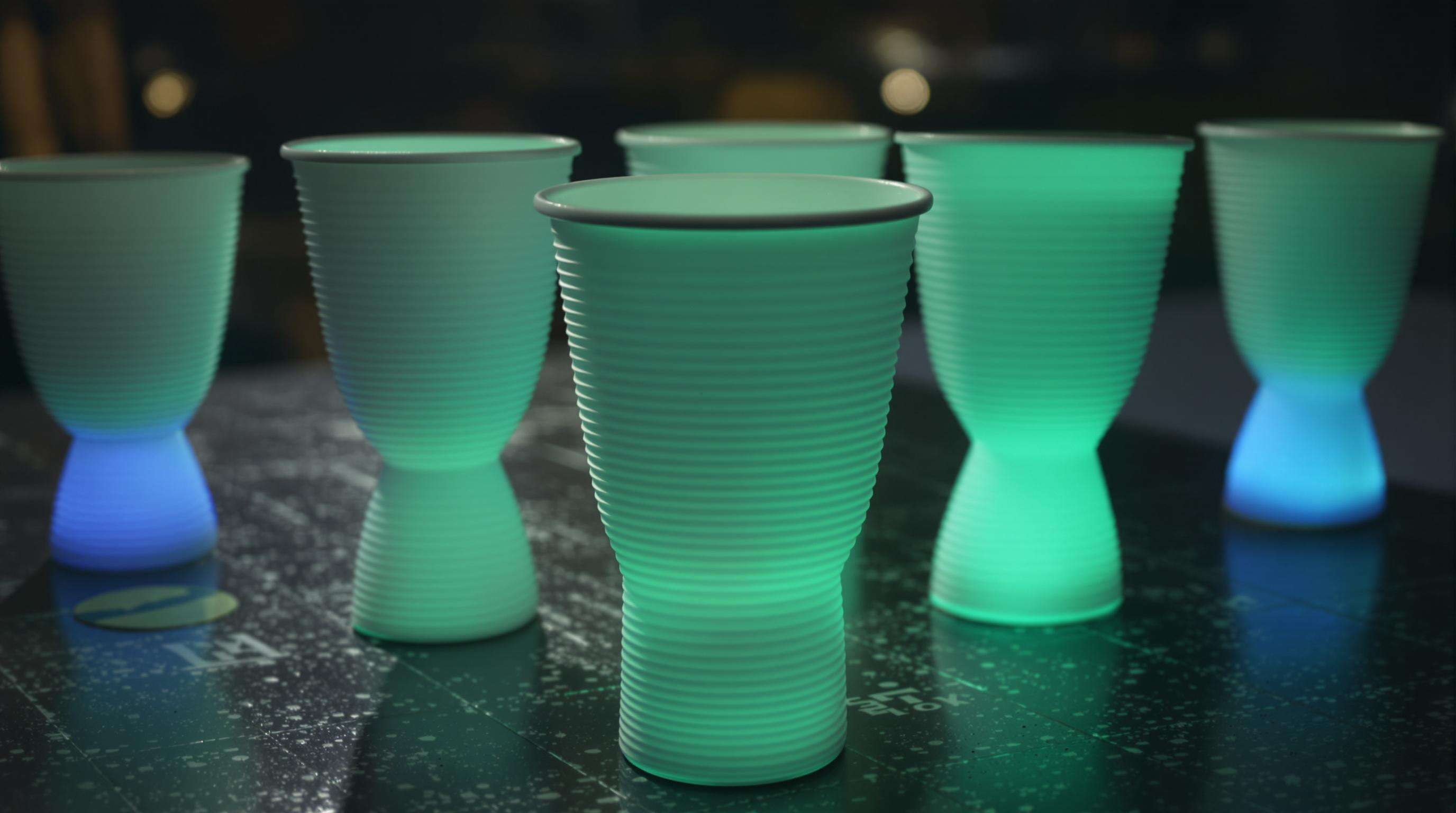 Modern glow-in-the-dark cups with textured grip and ergonomic design at a dimly lit event