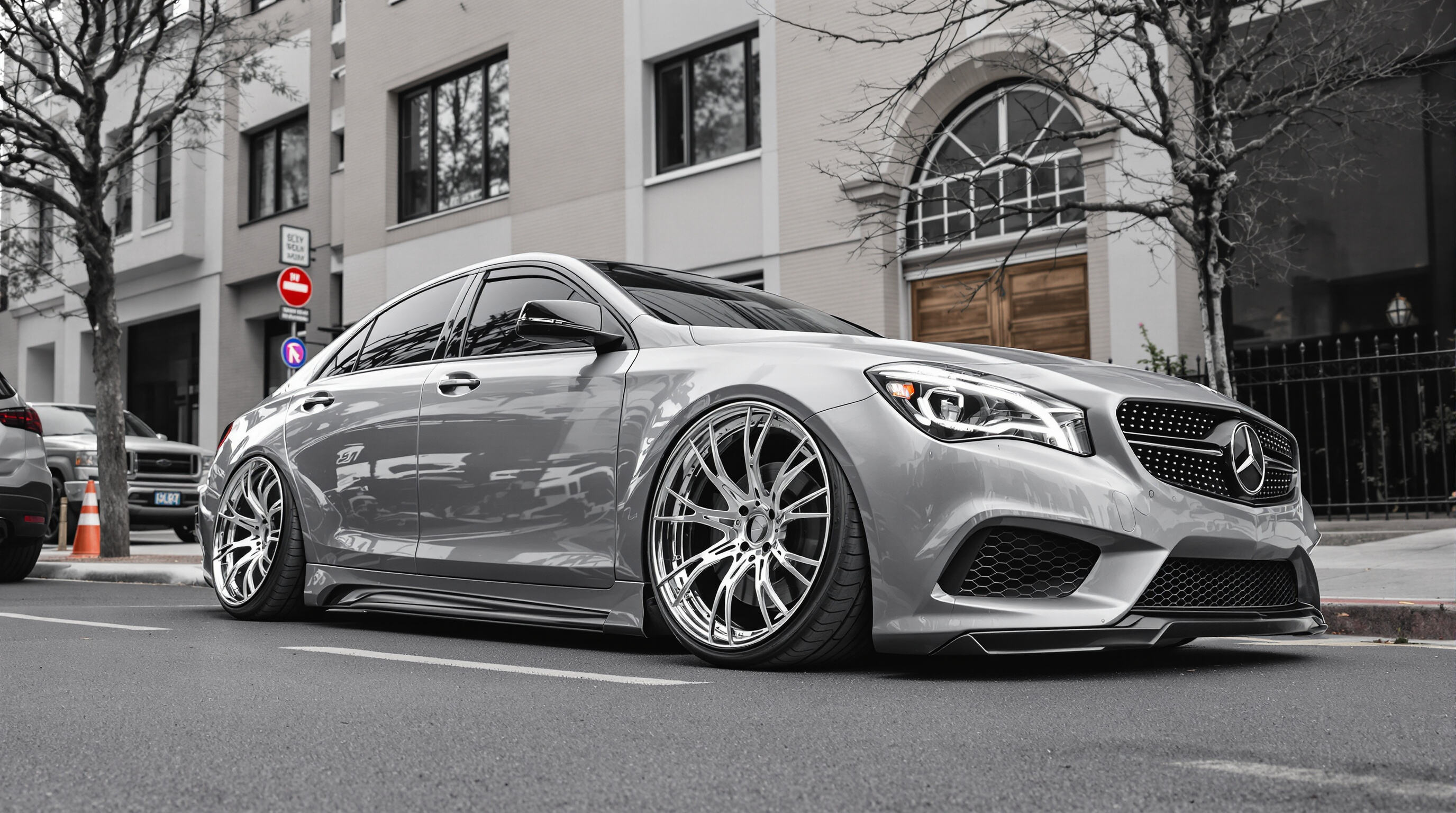 A modern car with oversized custom wheels filling its arches, shot on a city street