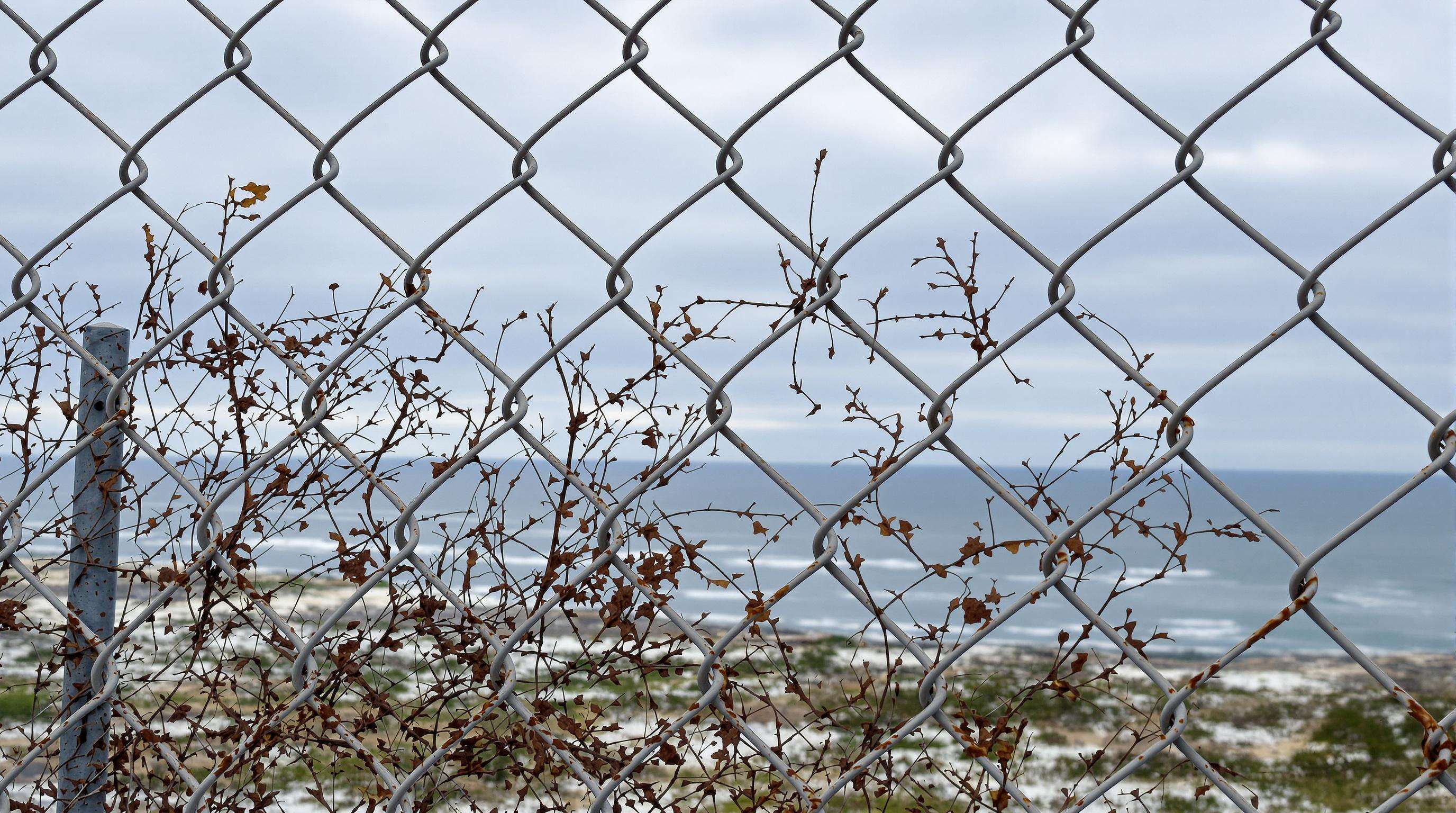 Photo of a chain link fence in a coastal area showing different rust and corrosion levels