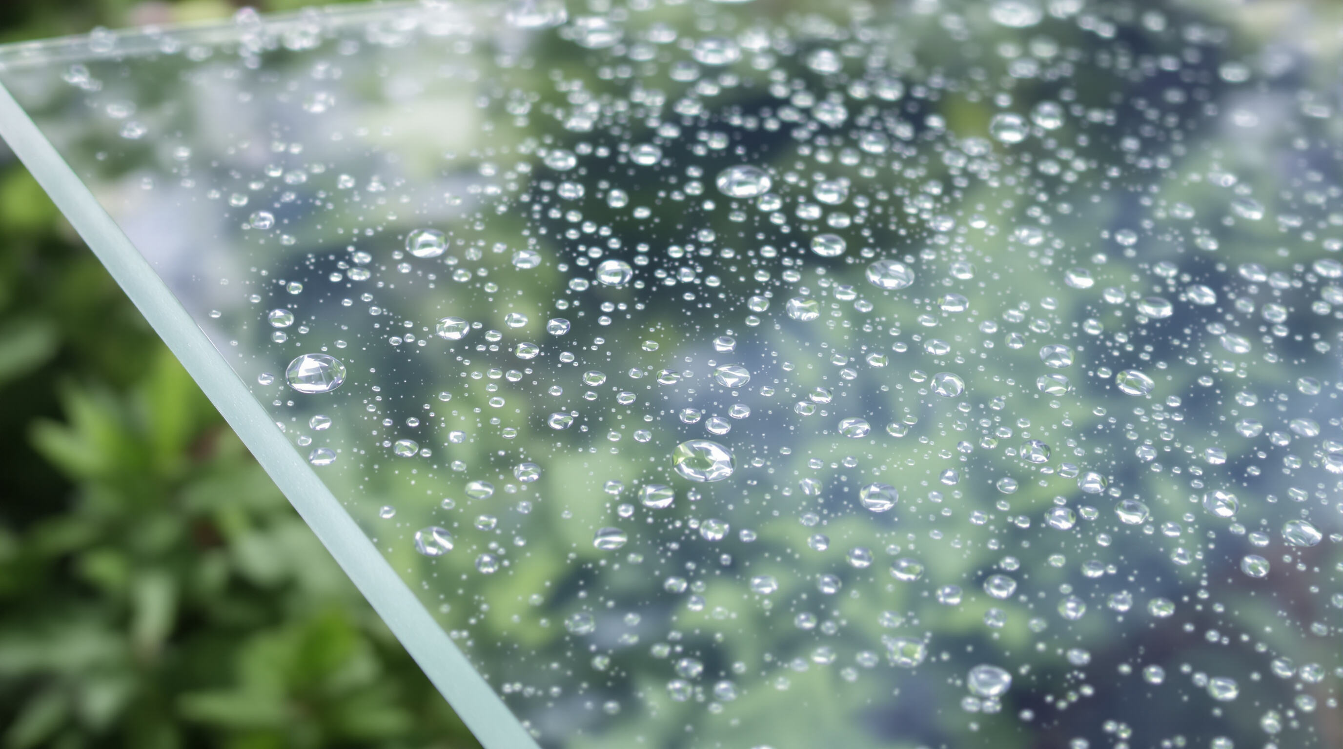Macro view of polycarbonate sheet outdoors with water beading and subtle anti-reflective surface