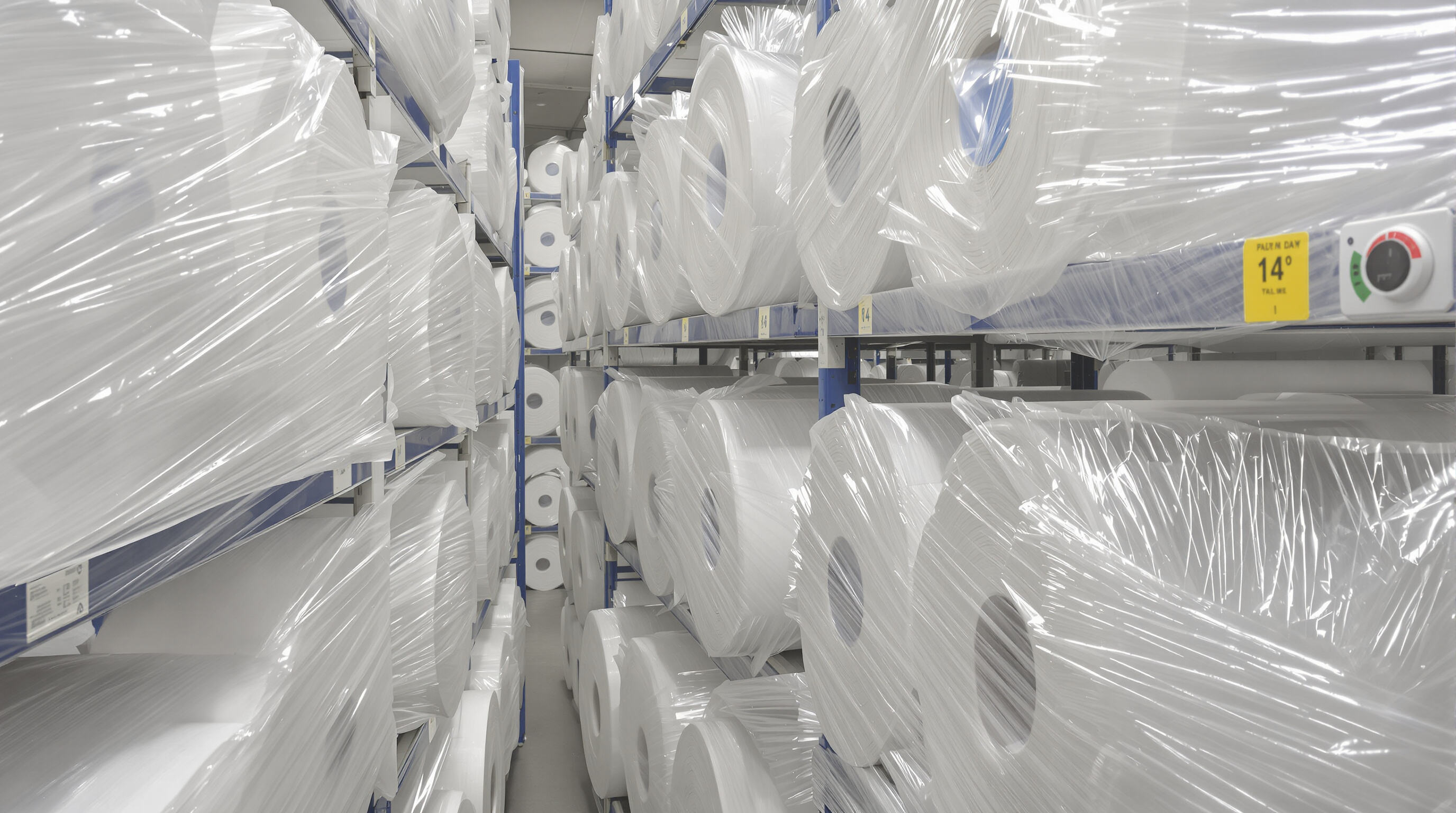 Climate-controlled storage with cleanroom paper rolls on shelves, vacuum-sealed and protected, with humidity and temperature sensors