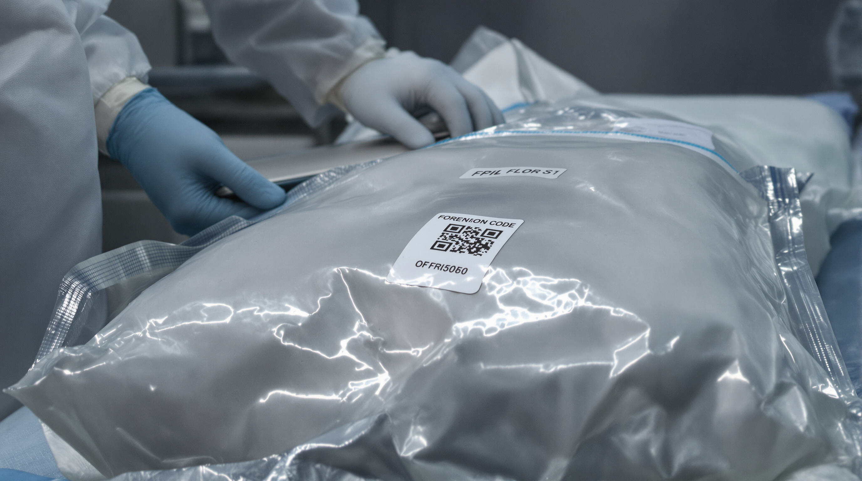 Forensic technician scanning a digitally labeled body bag in a morgue