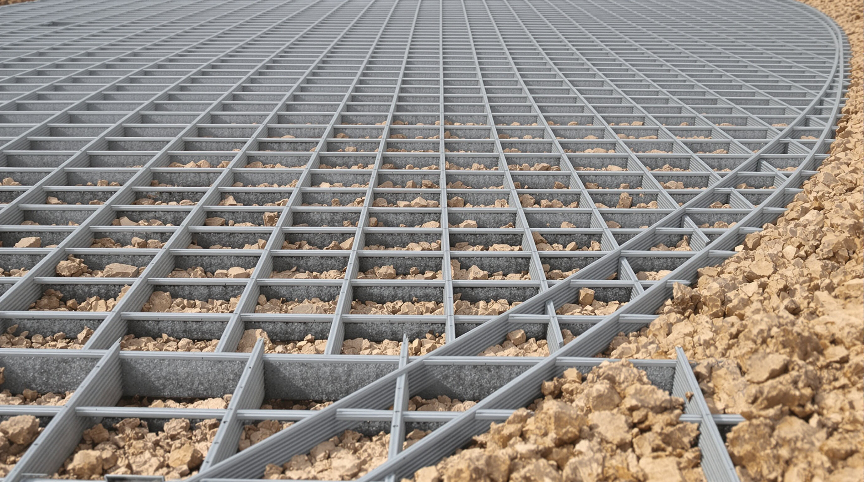 Close-up of a uniaxial geogrid showing long straight ribs and rectangular openings set in compacted soil