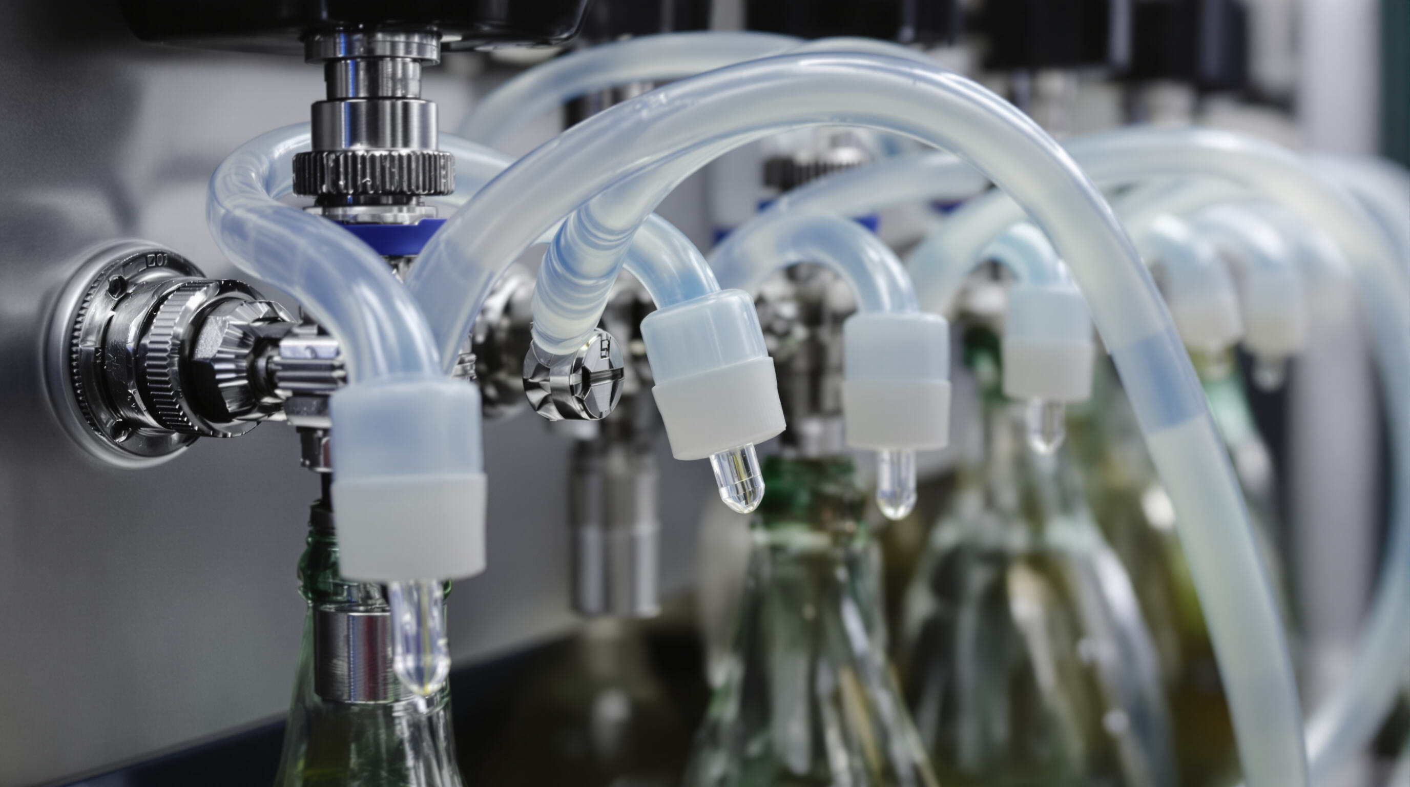 Silicone tubing in a beverage dispensing system, connected to metal valves and glass bottles