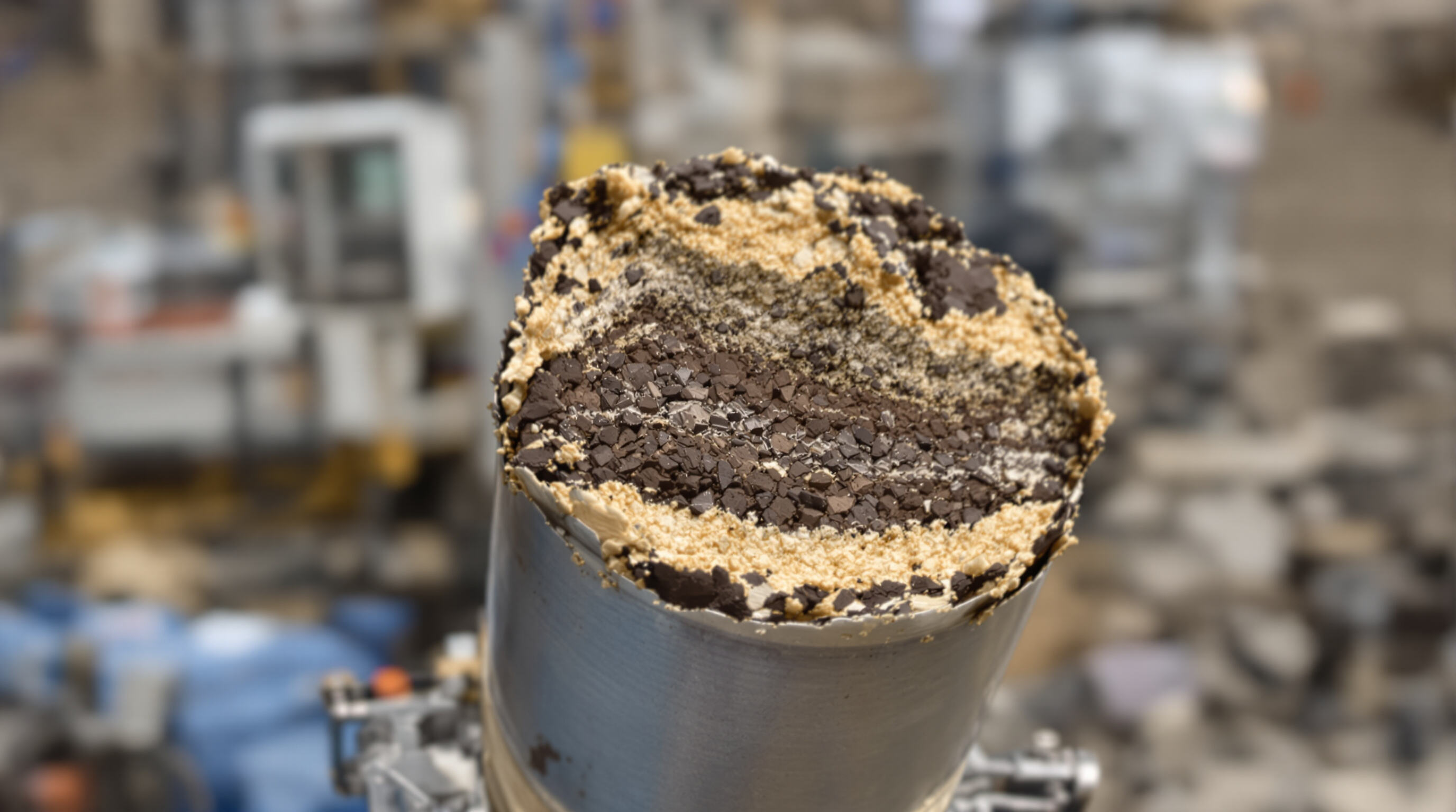 Pristine geological core sample in metal barrel, visible rock layers with little damage