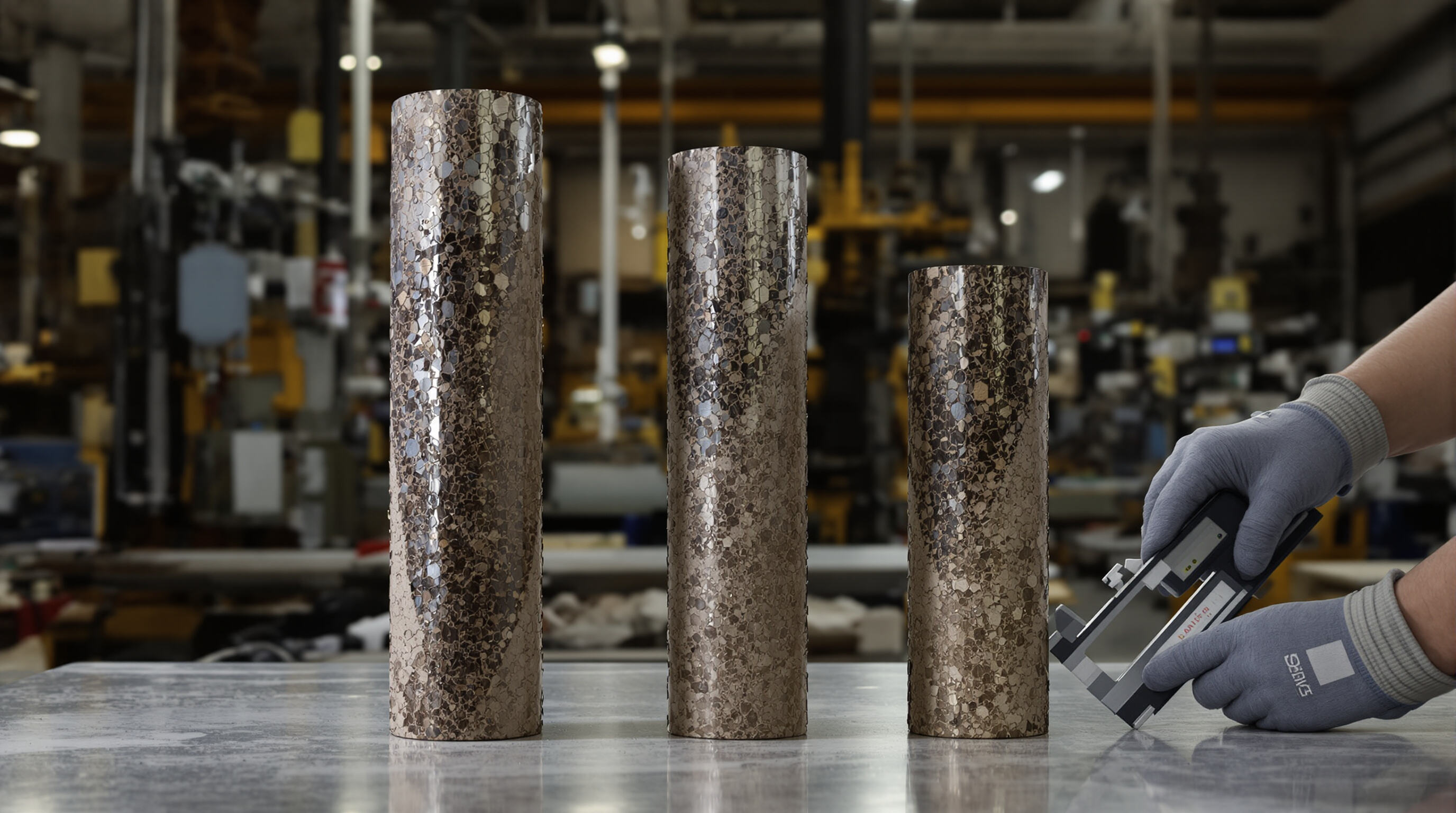 Three core barrels of different diameters being measured in an industrial workshop