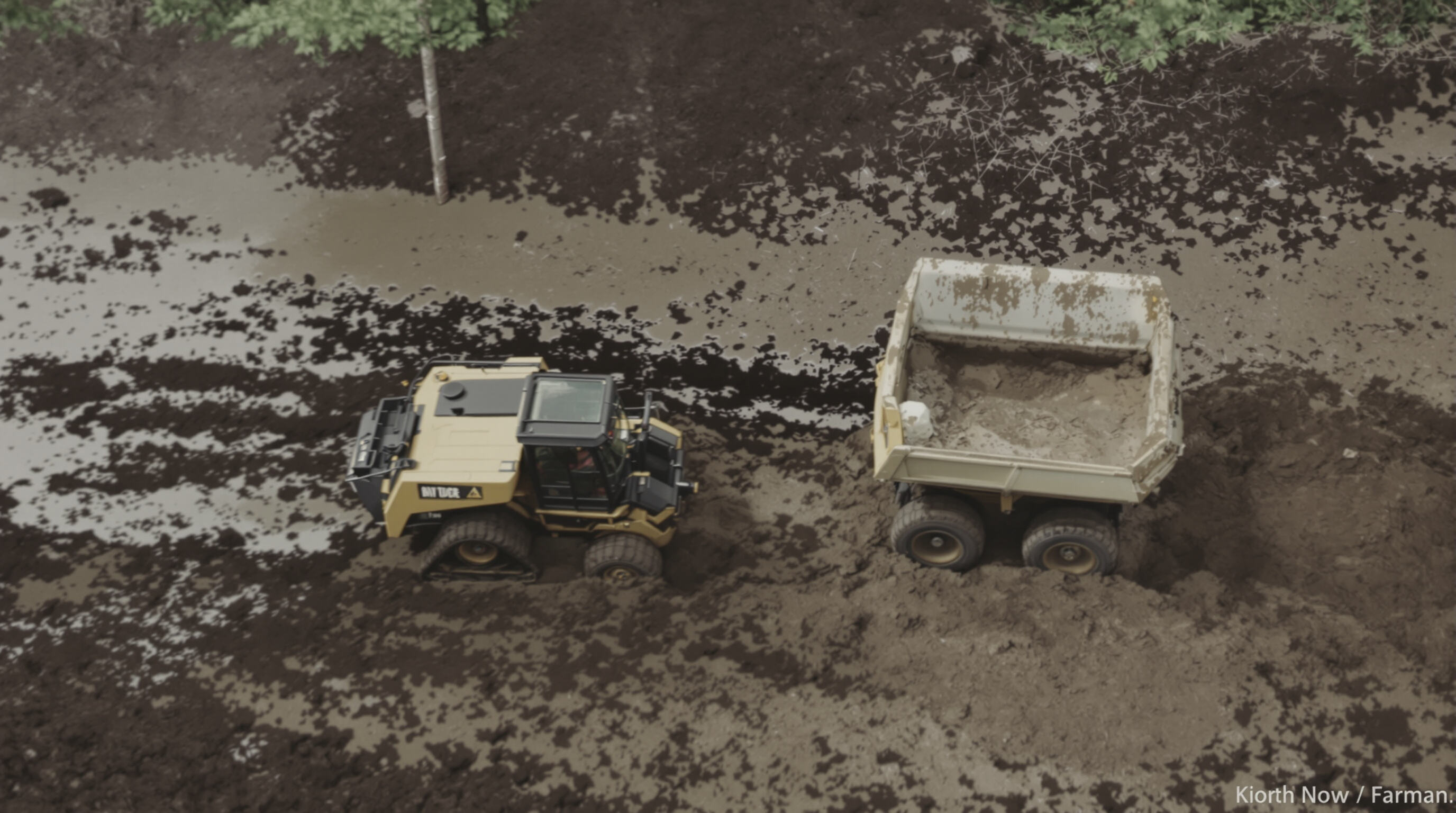 Tracked dumper traversing mud while wheeled dumper sinks nearby