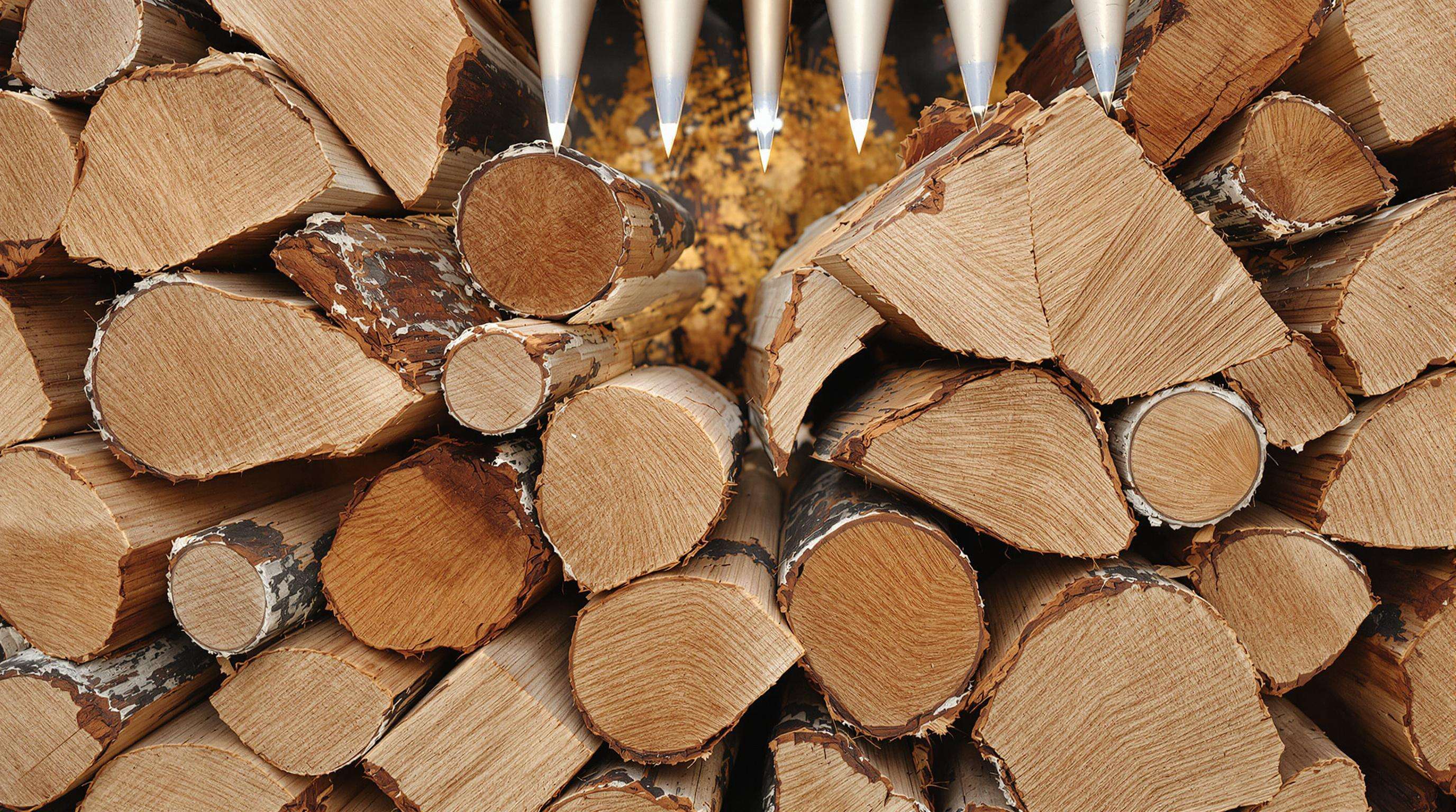 Oak and pine logs with distinct grain textures and chipper shredder blades in background