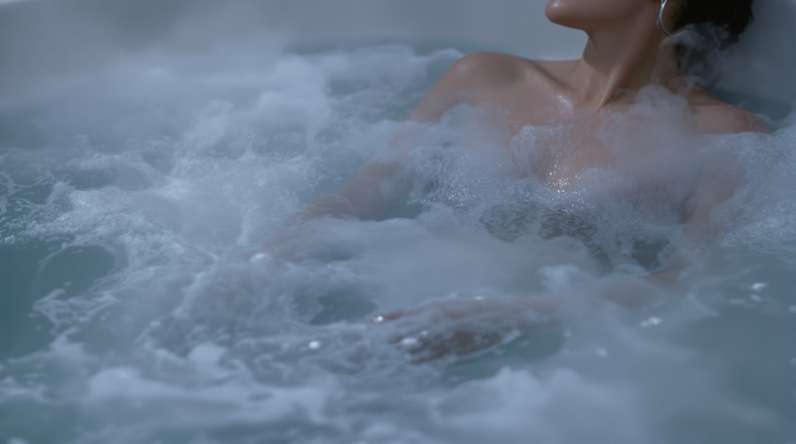 A person soaking in a modern Jacuzzi, surrounded by warm water and active jets