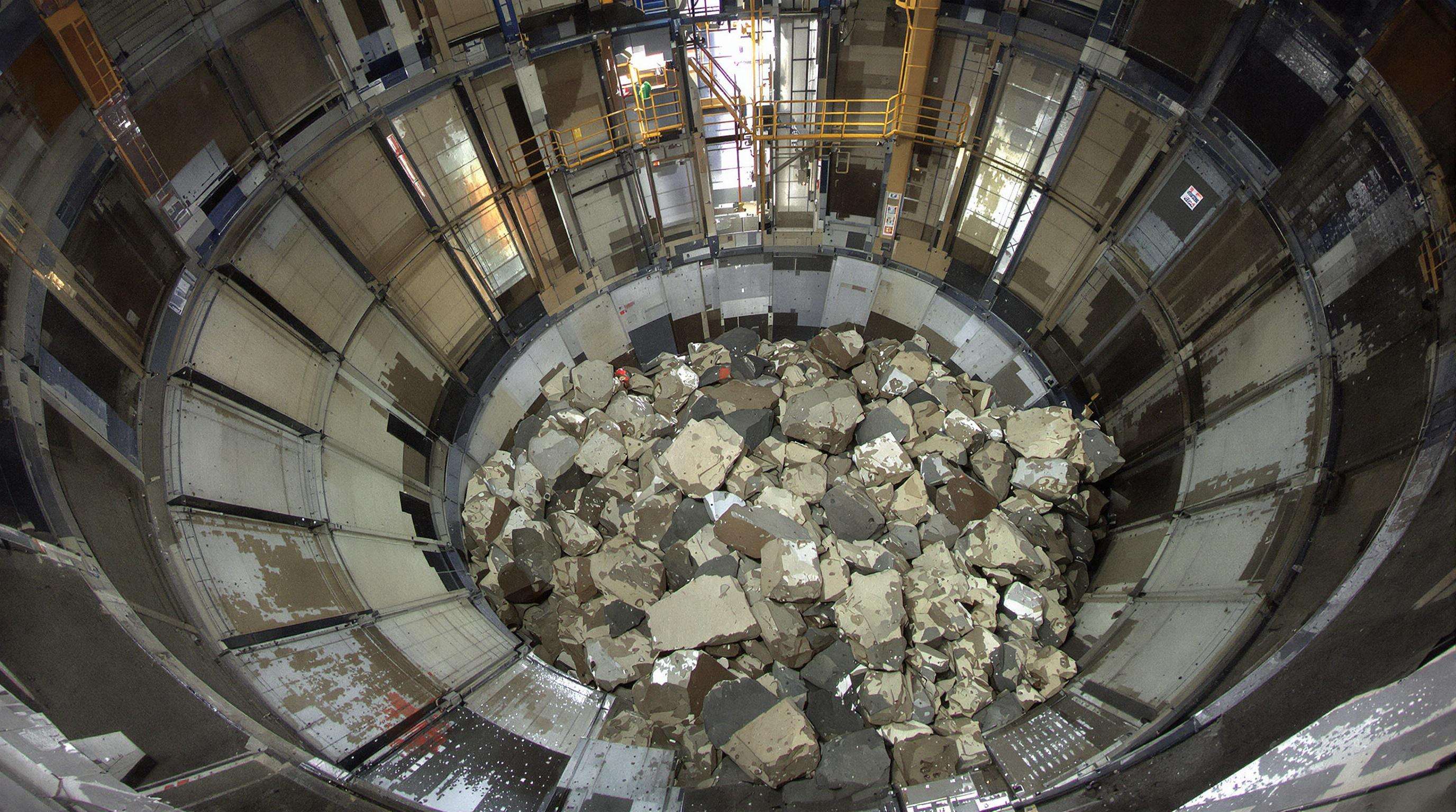 Crushing machine with metallic liner plates inside, showing ore impacting interiors in a mining facility
