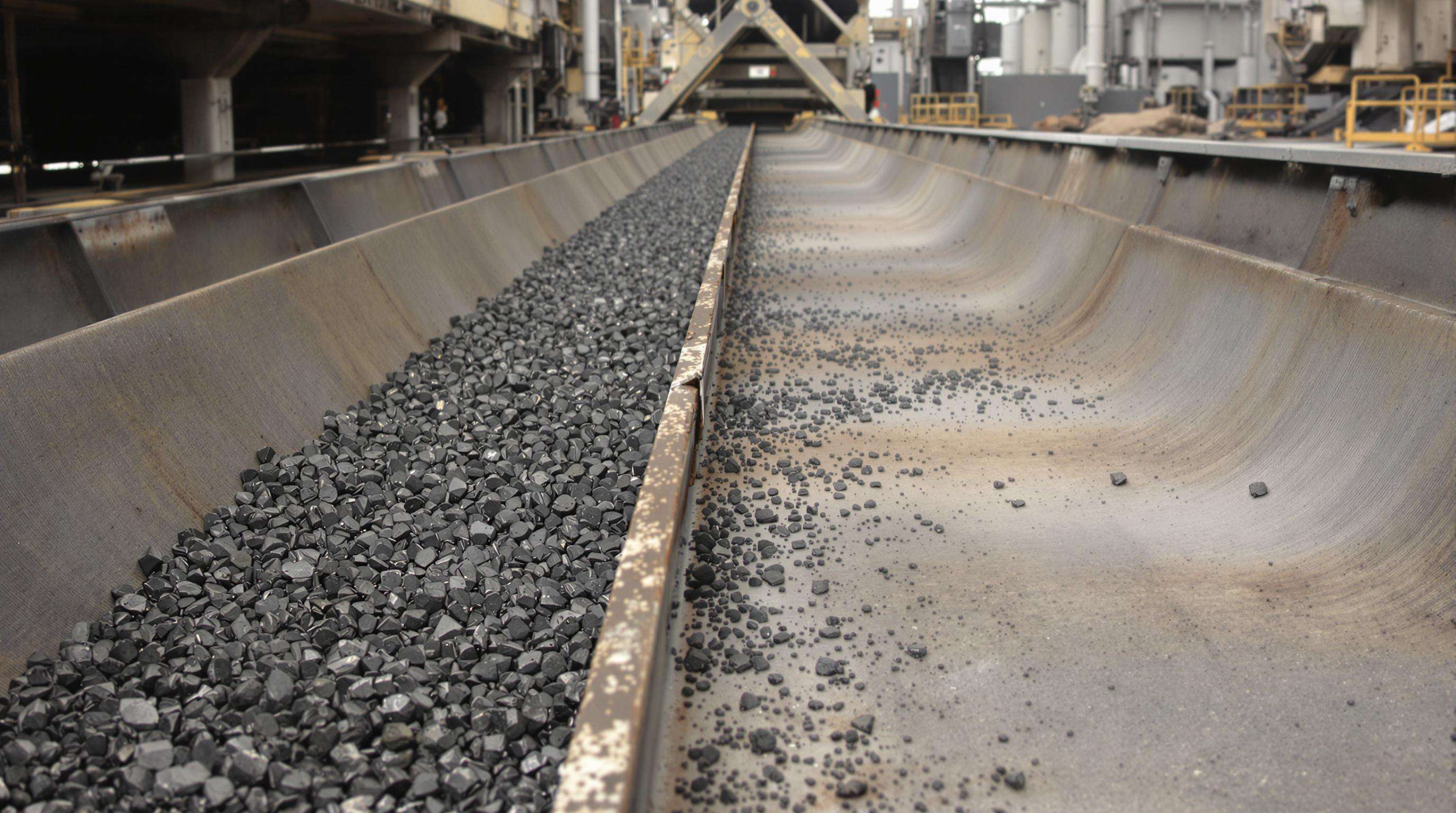 Mining conveyor system with metallic wear-resistant liners at transfer point, handling dark ore material
