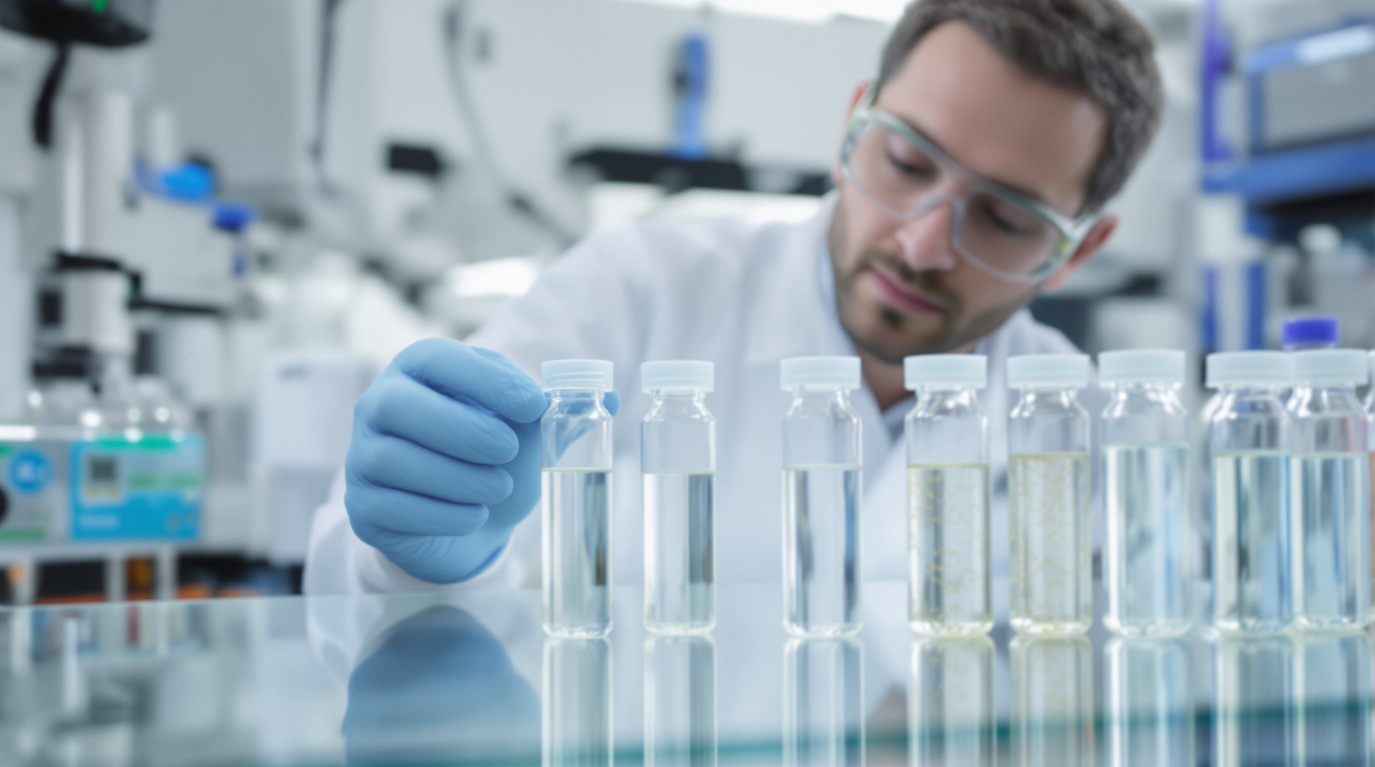 Scientist in a modern laboratory examining nano-enhanced and bio-based acrylic resin samples on a glass surface.