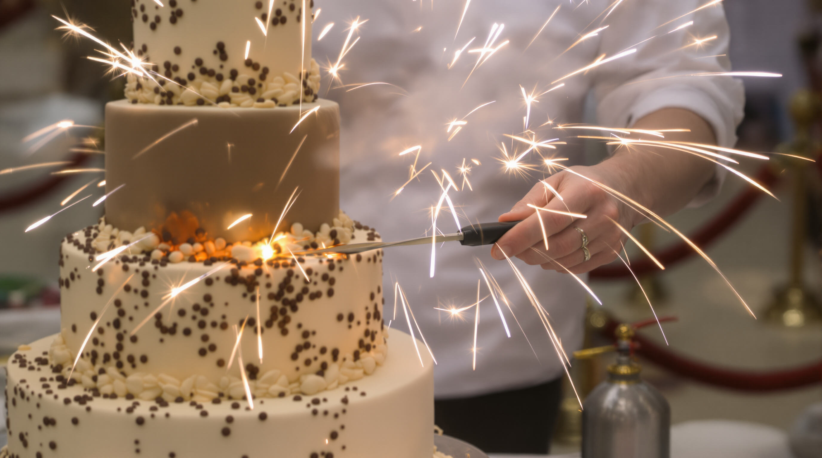 Pastry chef safely installing cake fireworks on a decorated cake with safety equipment