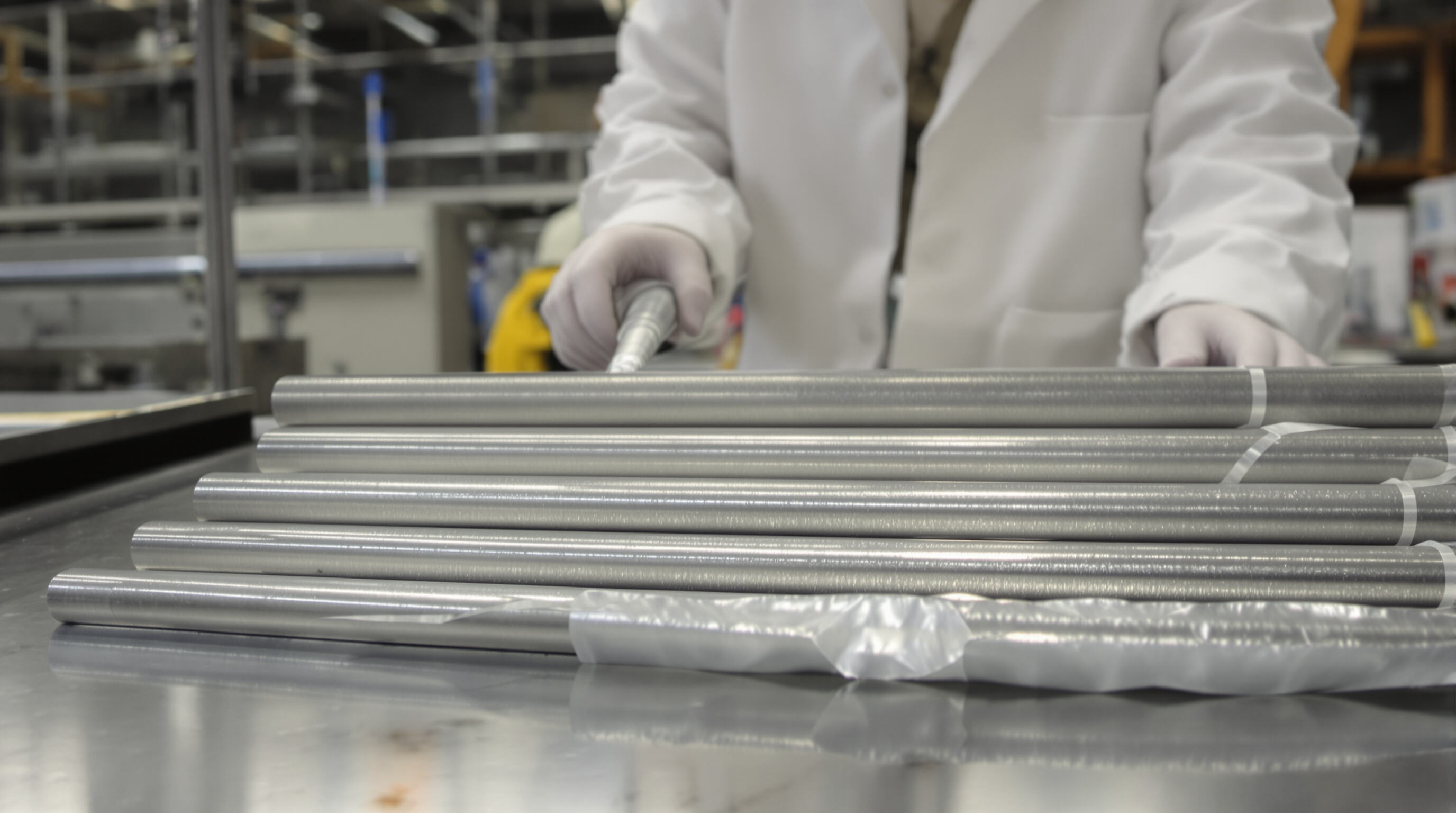 Scientist examining aluminum rods of different temper conditions in a laboratory setting