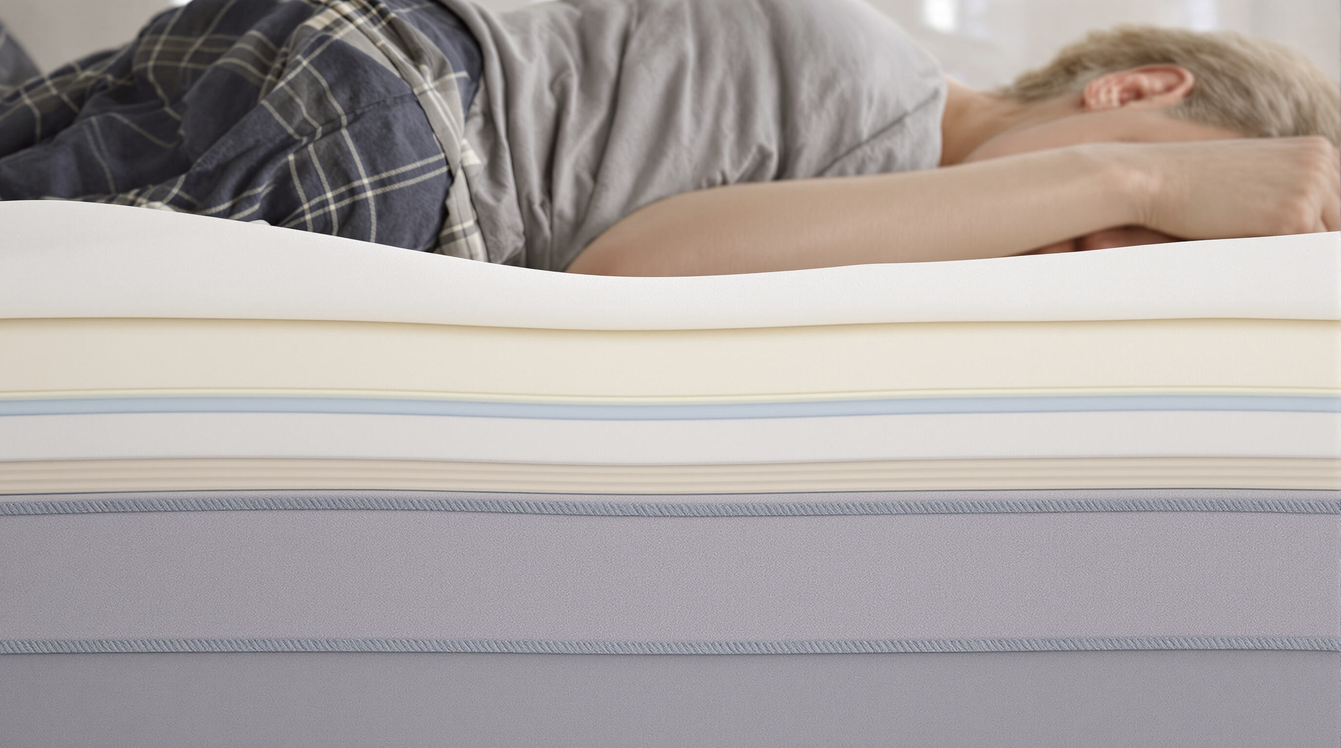 Side sleeper on bed with supportive mattress pad aligning shoulders and hips