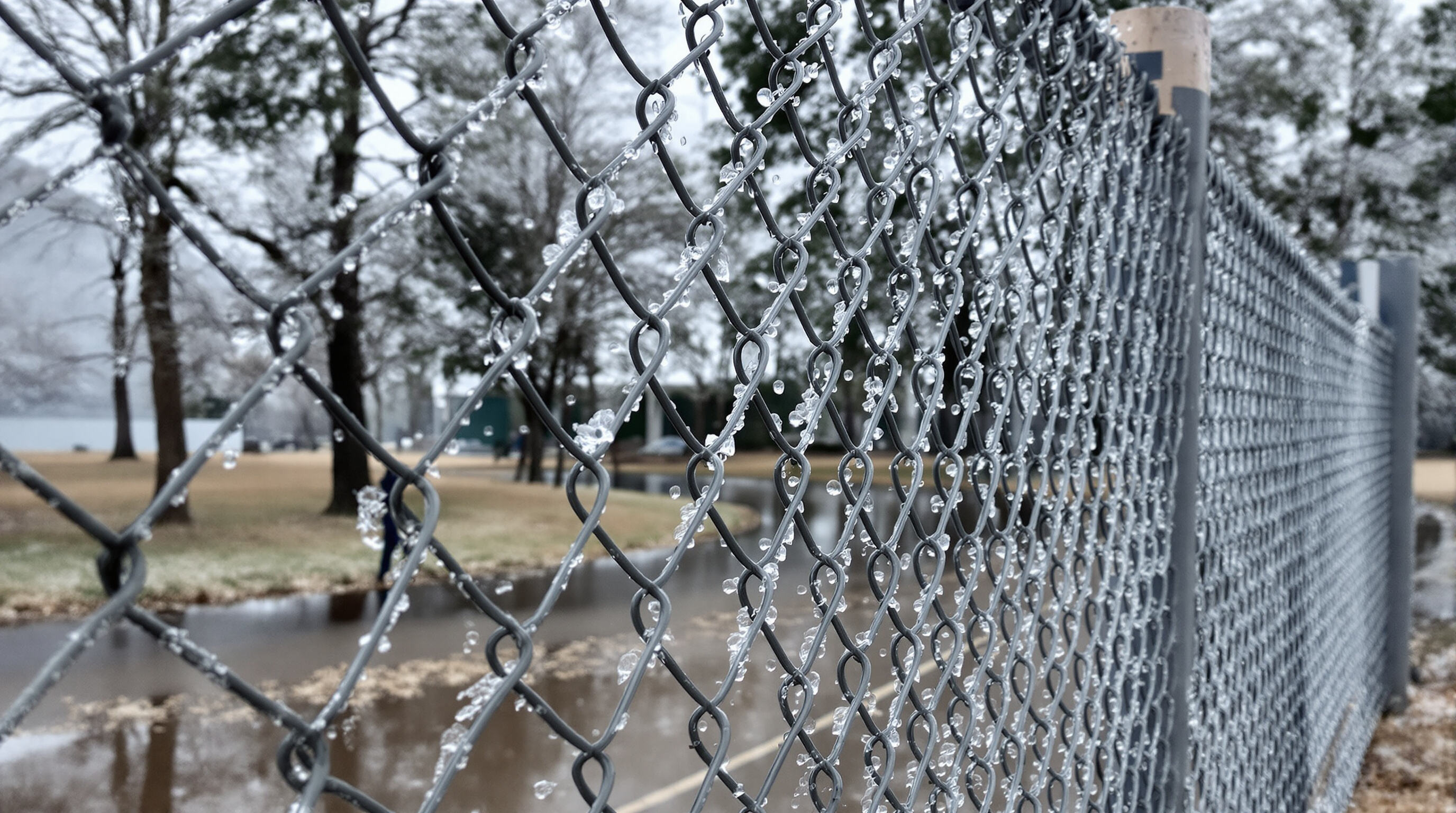 Chain link fence showing resilience in harsh weather with rain, frost, and strong winds